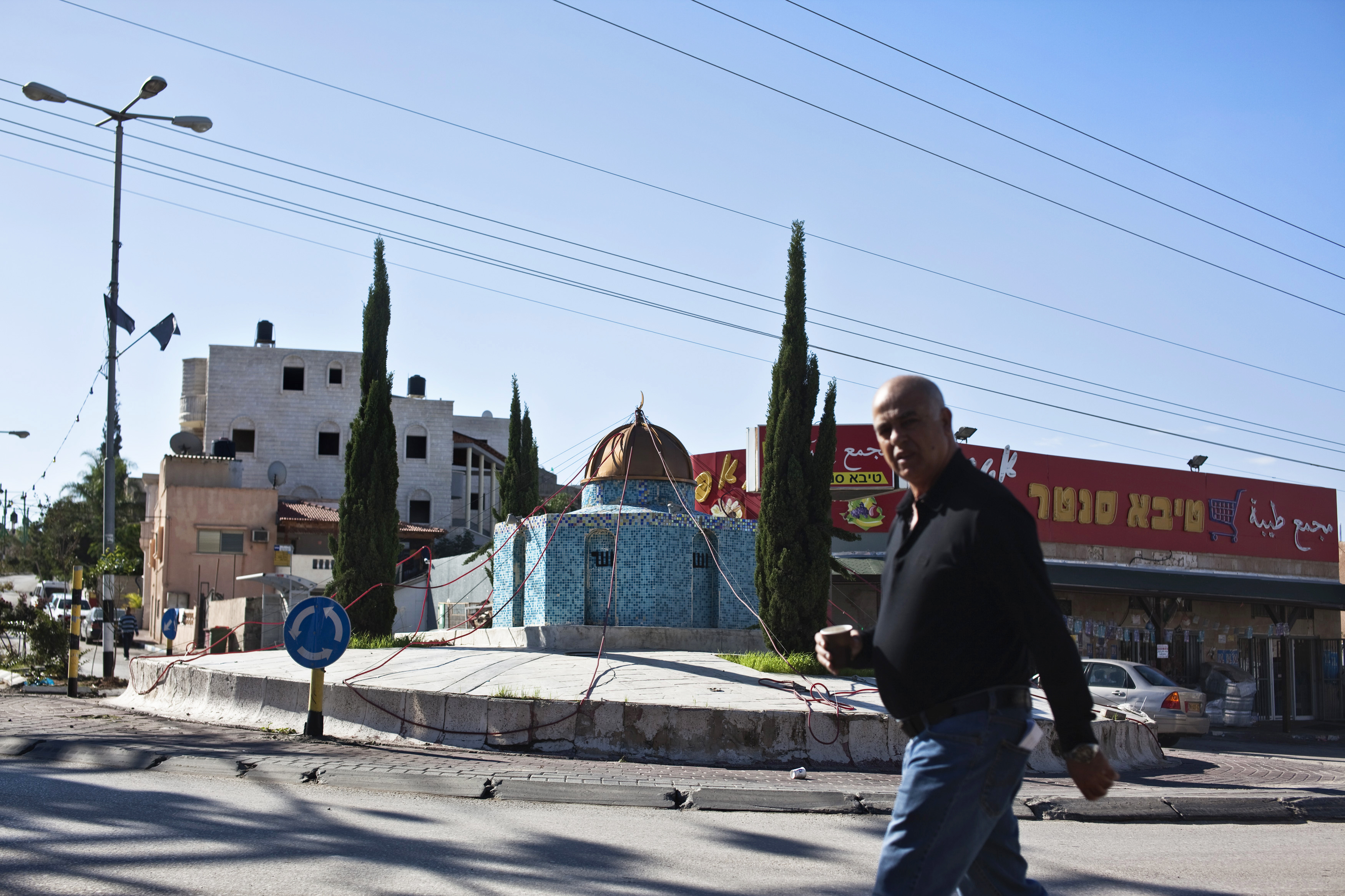 A man walks in front of a replica of the Dome of the Rock mosque