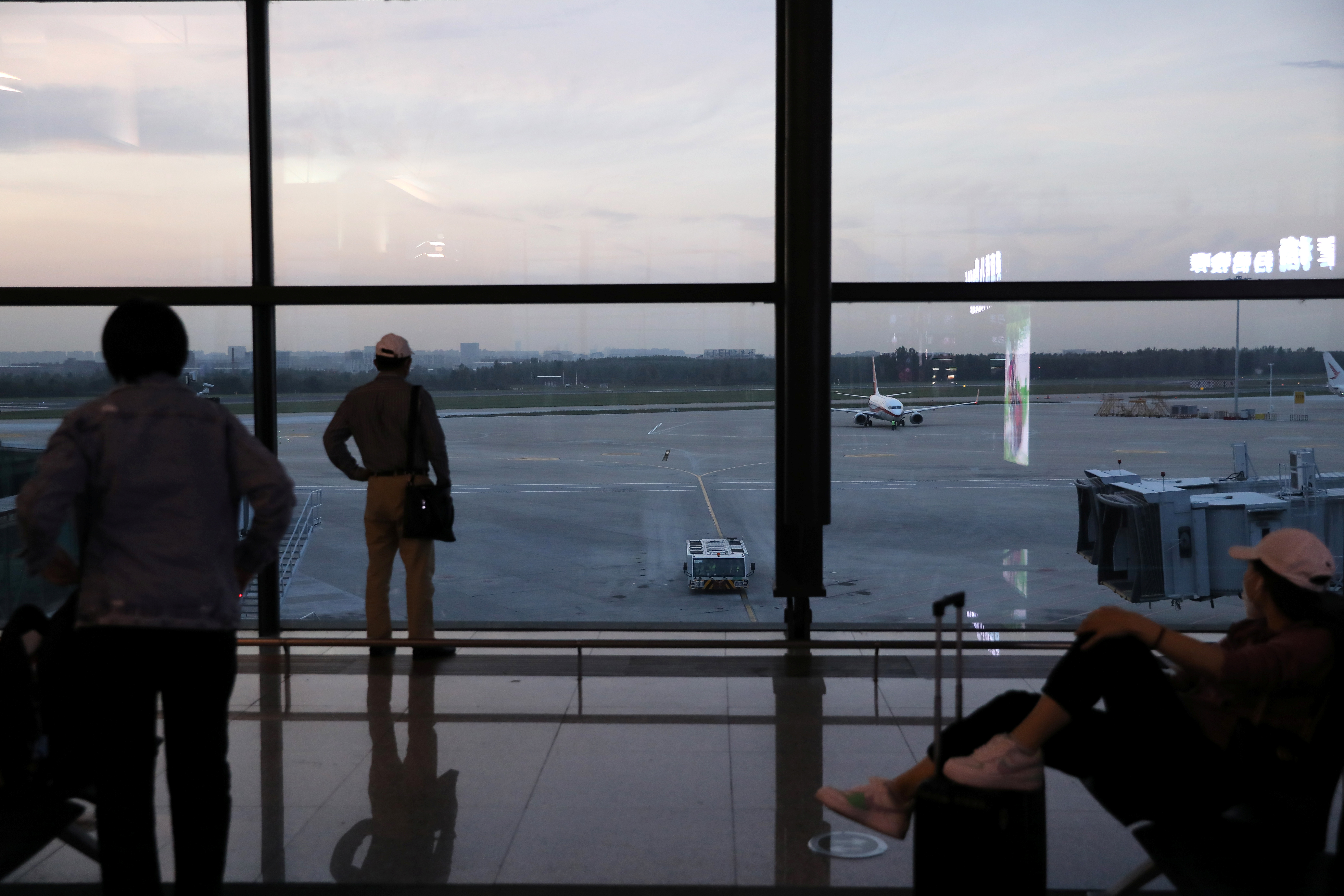 Travellers look at the tarmac of the Taoxian International Airport in Shenyang, Liaoning province, China.