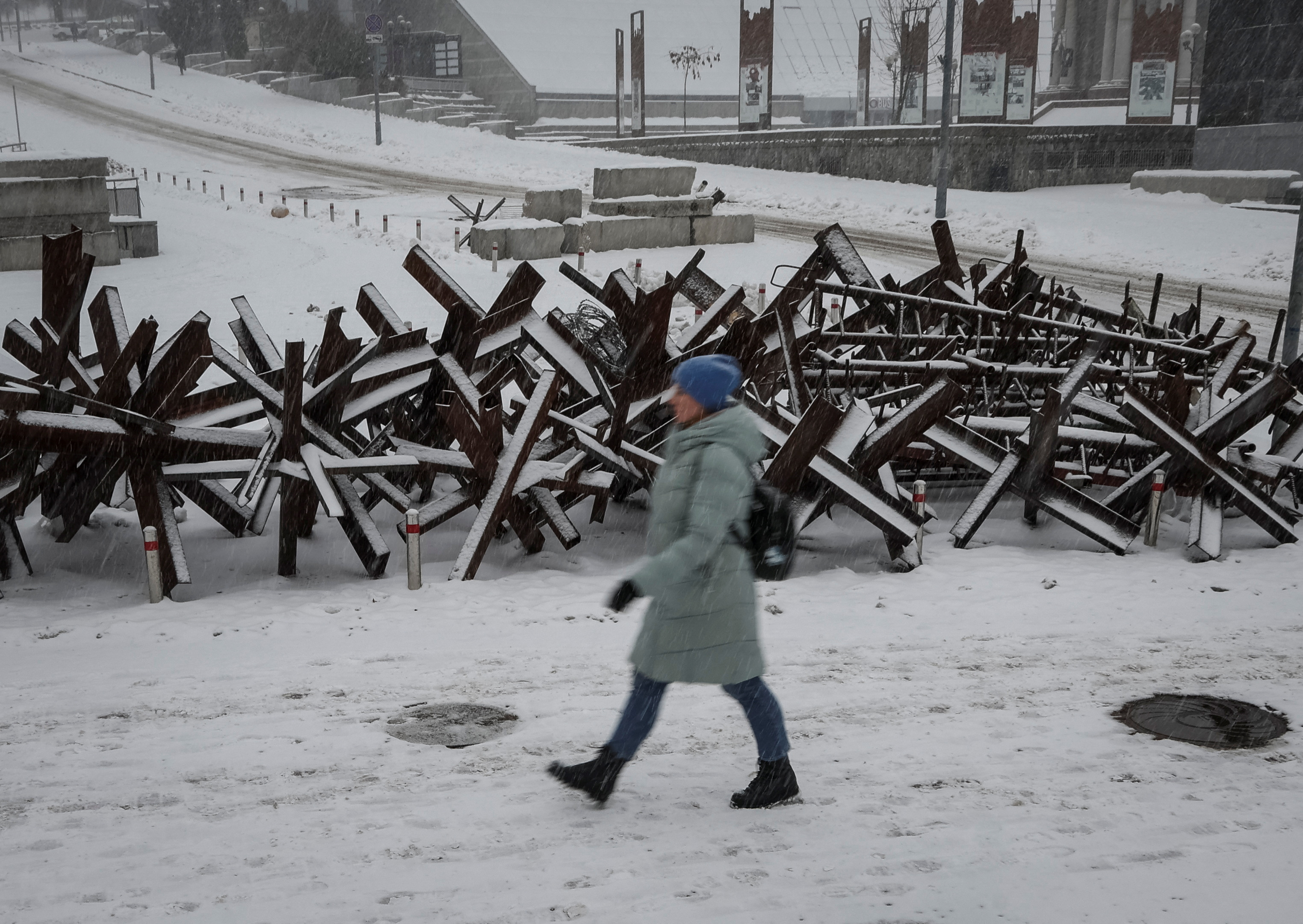 A woman walks down a street near anti-tank constructions amid a snowfall as Russia's invasion of Ukraine continues, in central Kyiv, Ukraine December 7, 2022.