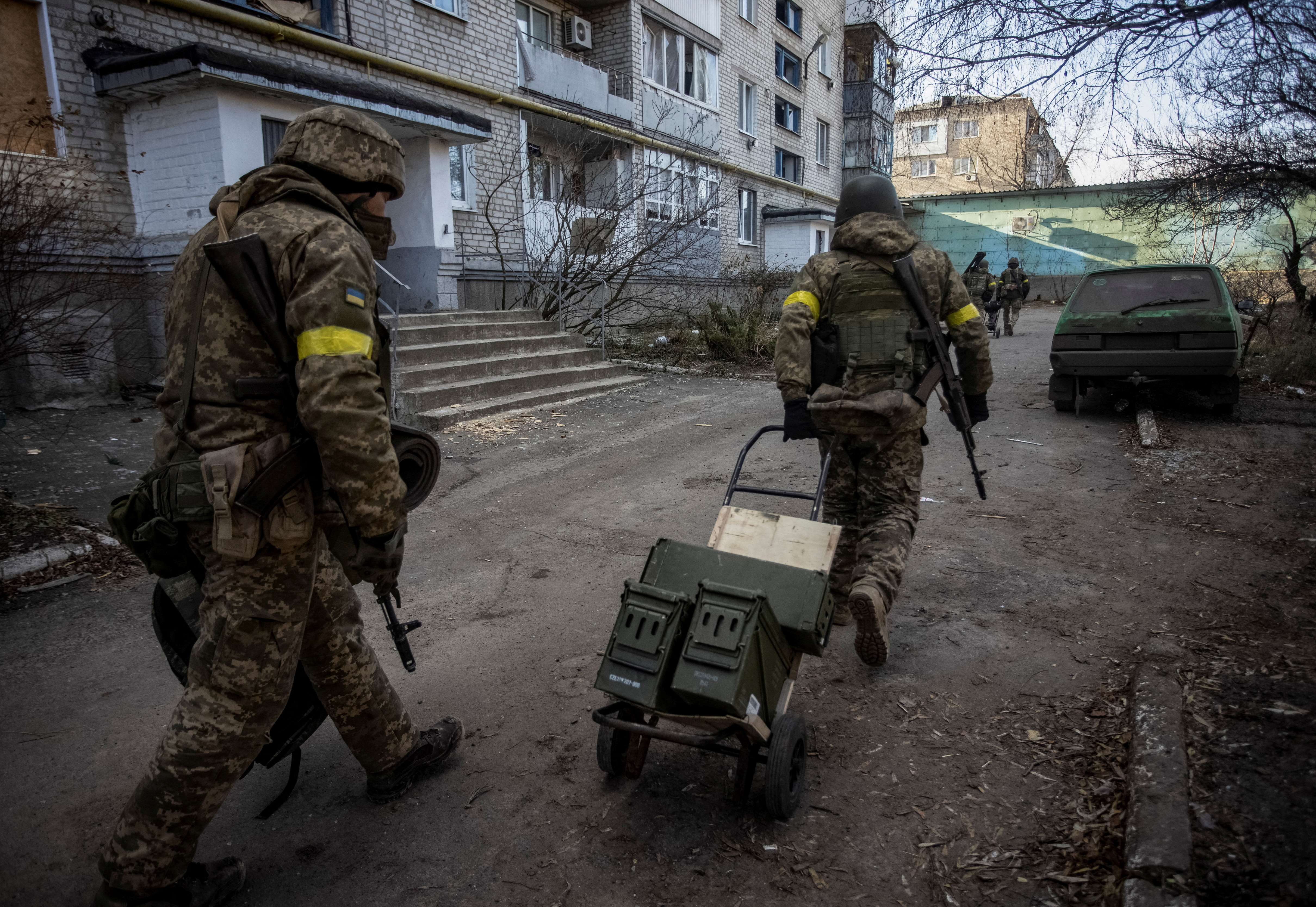 Ukrainian service members carry weapons on a dolly through a street in Bakhmut, Ukraine.