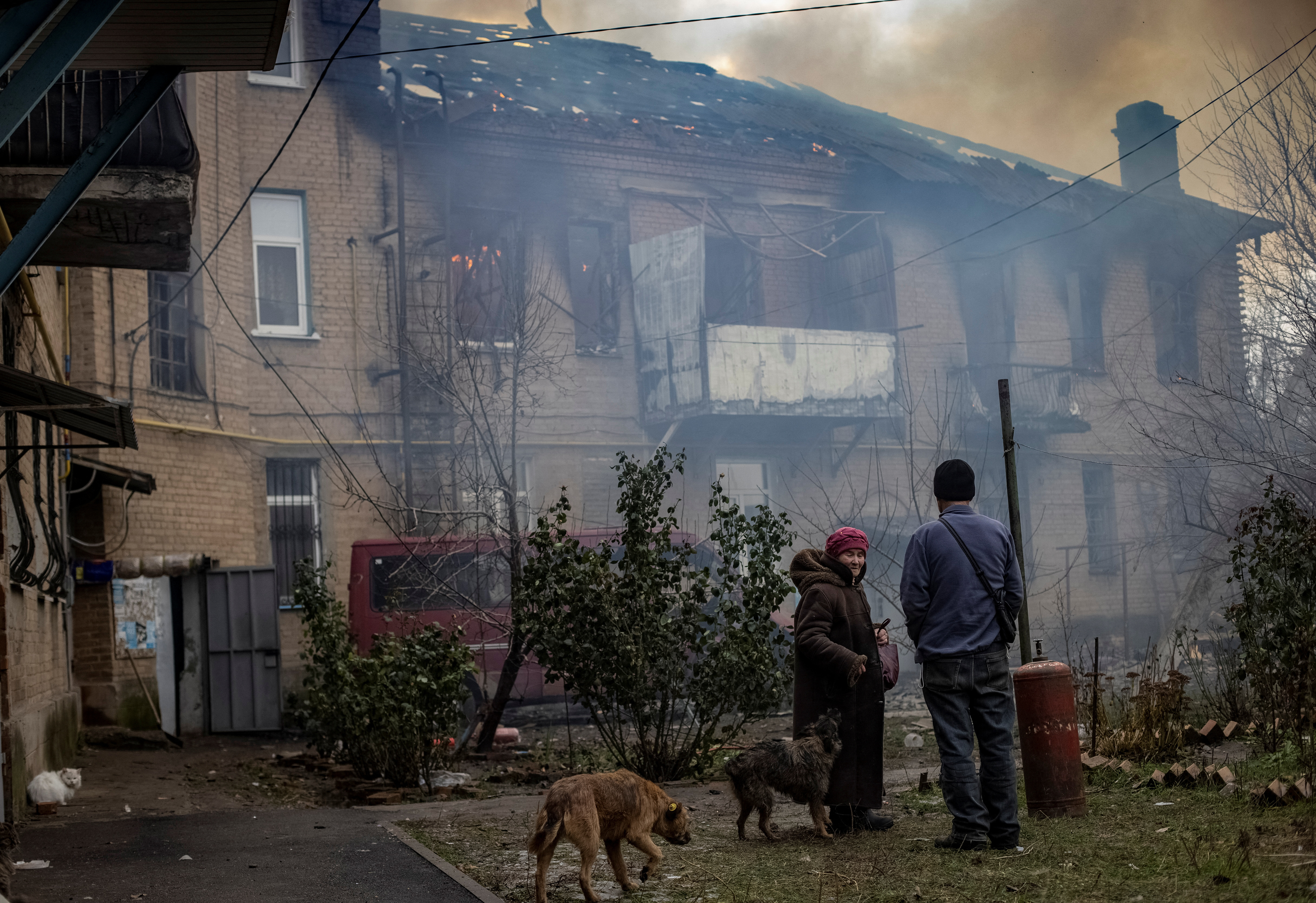 Residents stand in the yard of their destroyed apartment building looking at the smoke rise in Bakhmut, Ukraine.