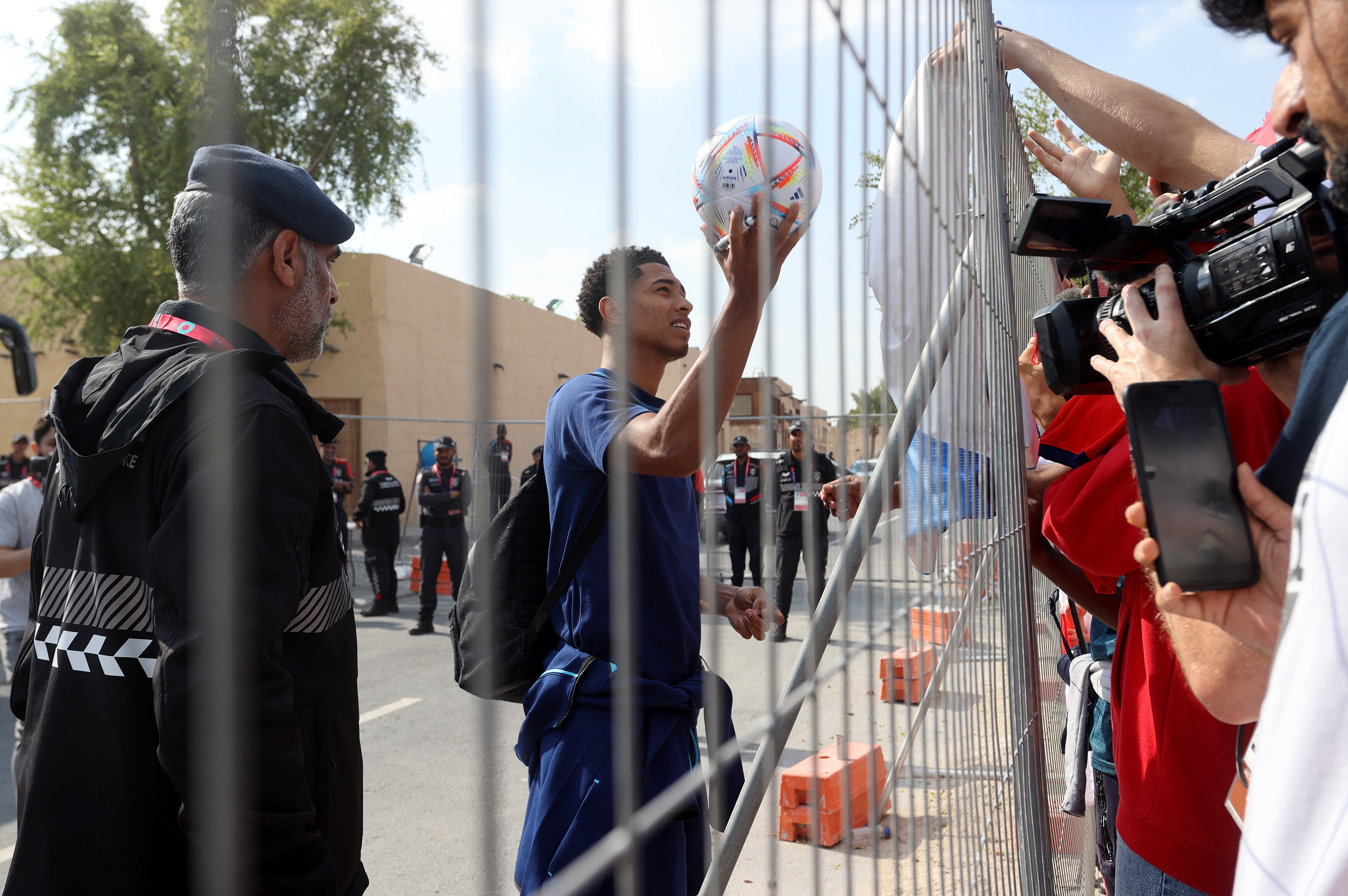 Soccer Football - FIFA World Cup Qatar 2022 - England depart from Qatar after losing their quarter final match against France - Al Wakrah, Qatar - December 11, 2022 England's Jude Bellingham signs a ball for fans as he leaves the hotel REUTERS/Ibraheem Al Omari