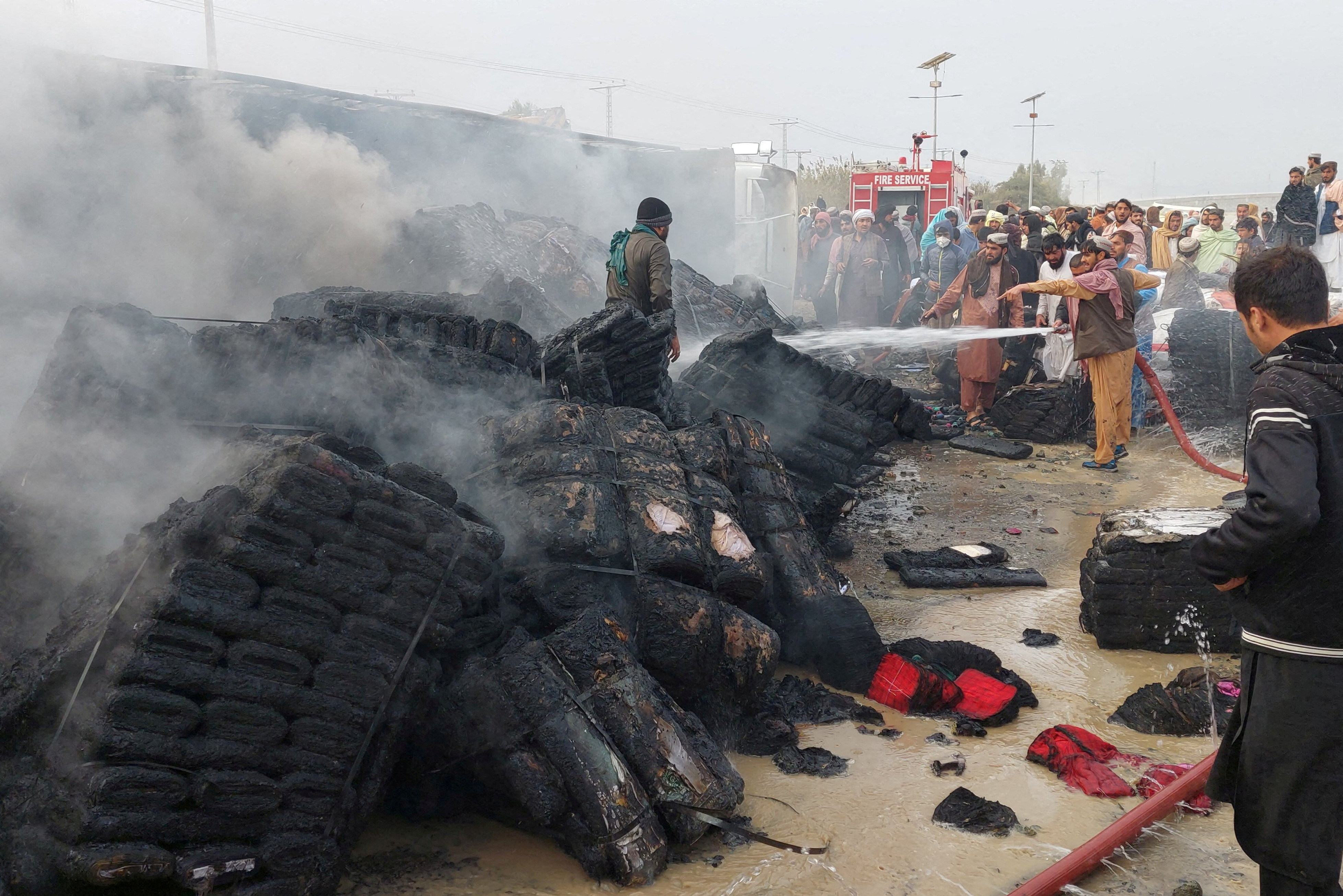 FILE PHOTO: People douse a cargo supply truck after it was hit during the artillery shelling, in the Pakistan-Afghanistan border town of Chaman, Pakistan, December 11, 2022. REUTERS/Abdul Khaliq Achakzai/File Photo