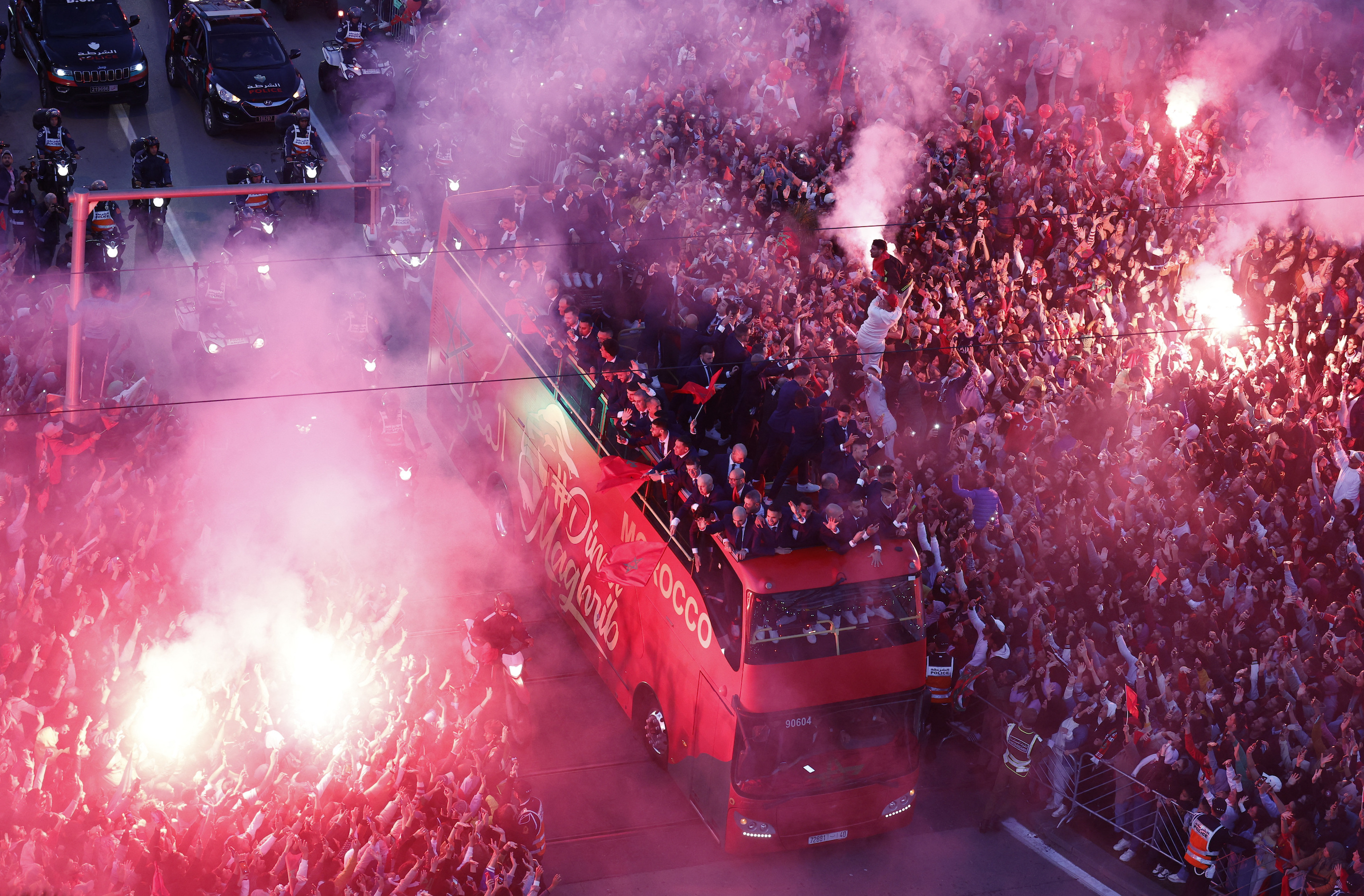 Fans celebrate with flares as Morocco players arrive on a bus