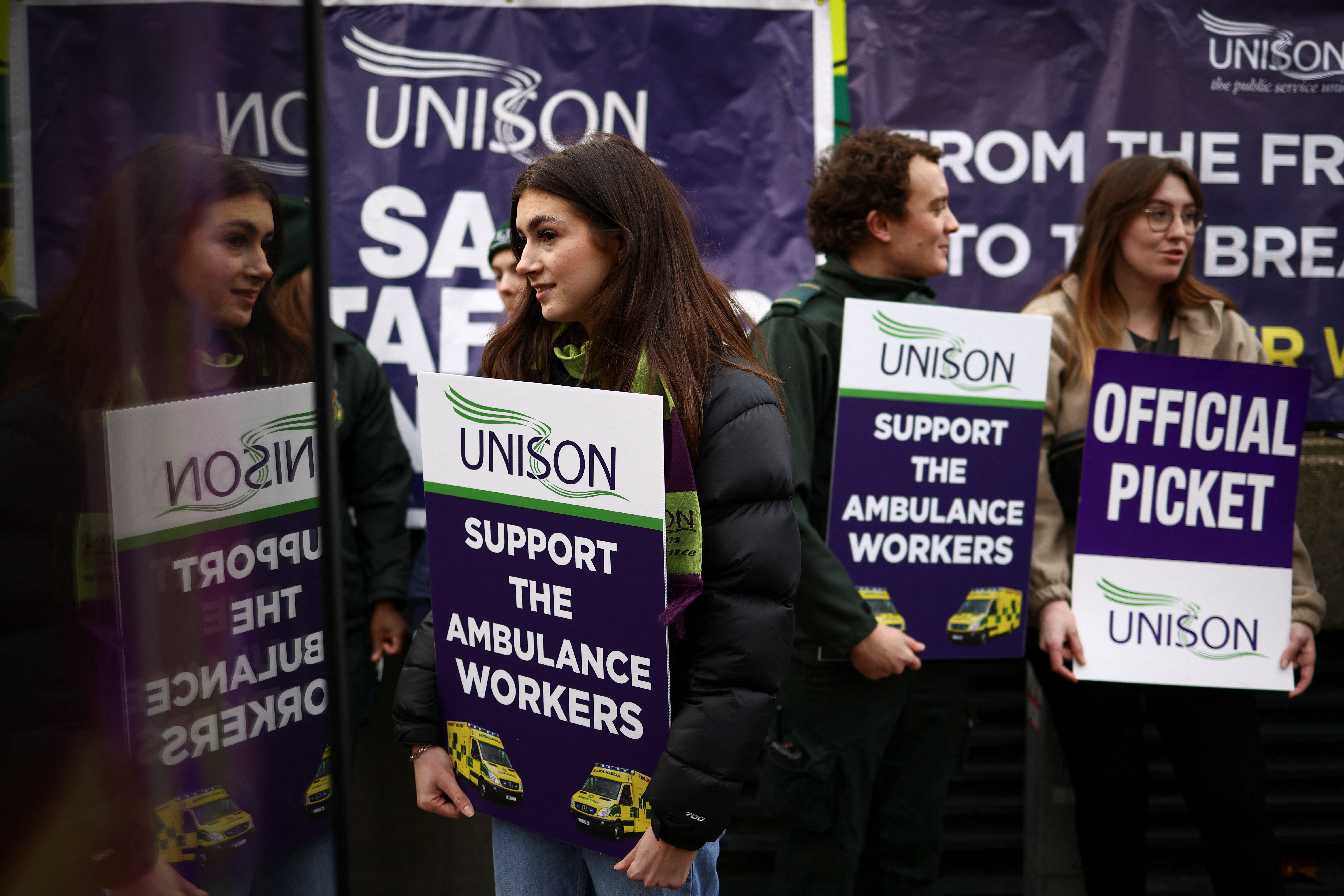 People hold signs, as ambulance workers strike