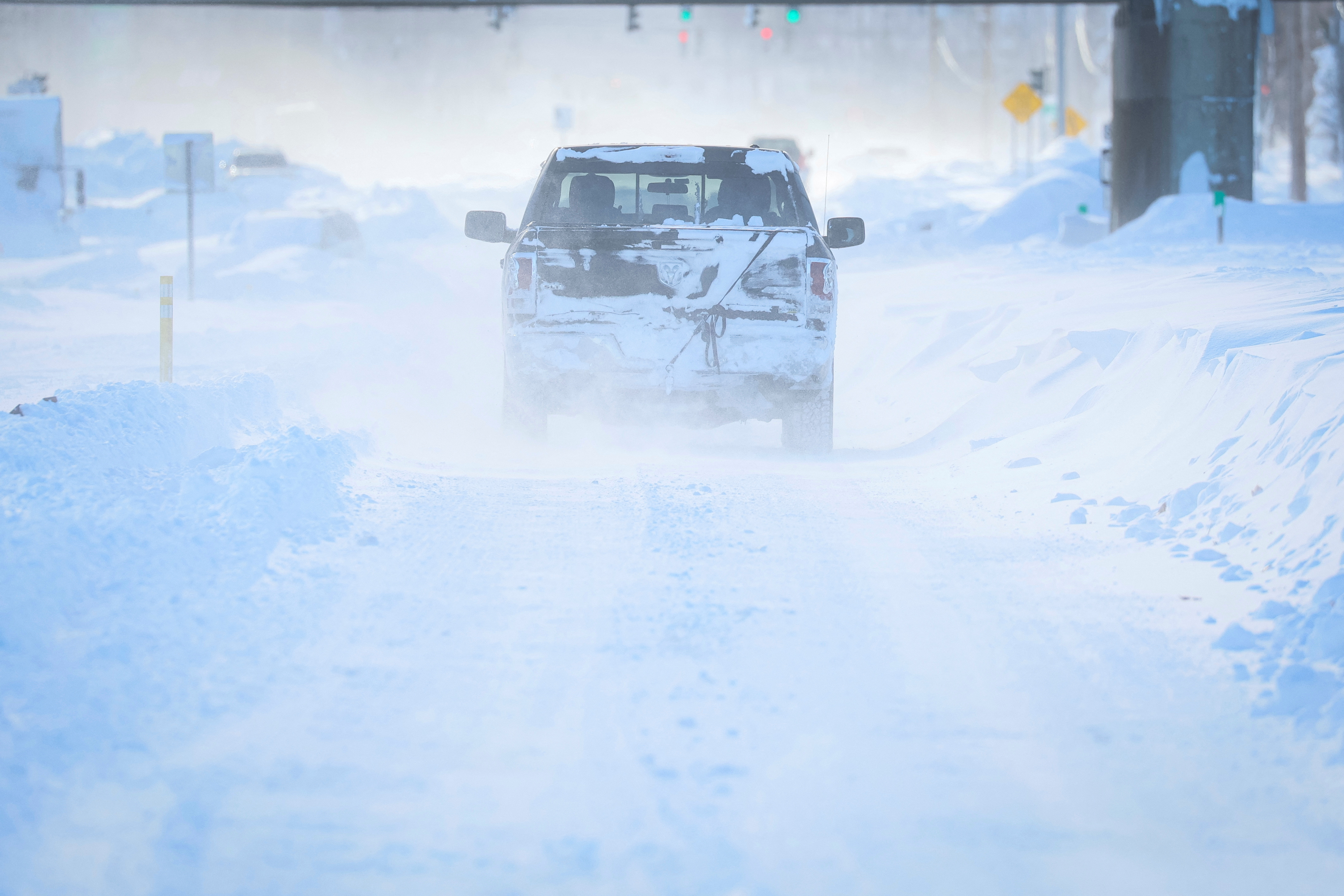 A truck drives in blowing snow