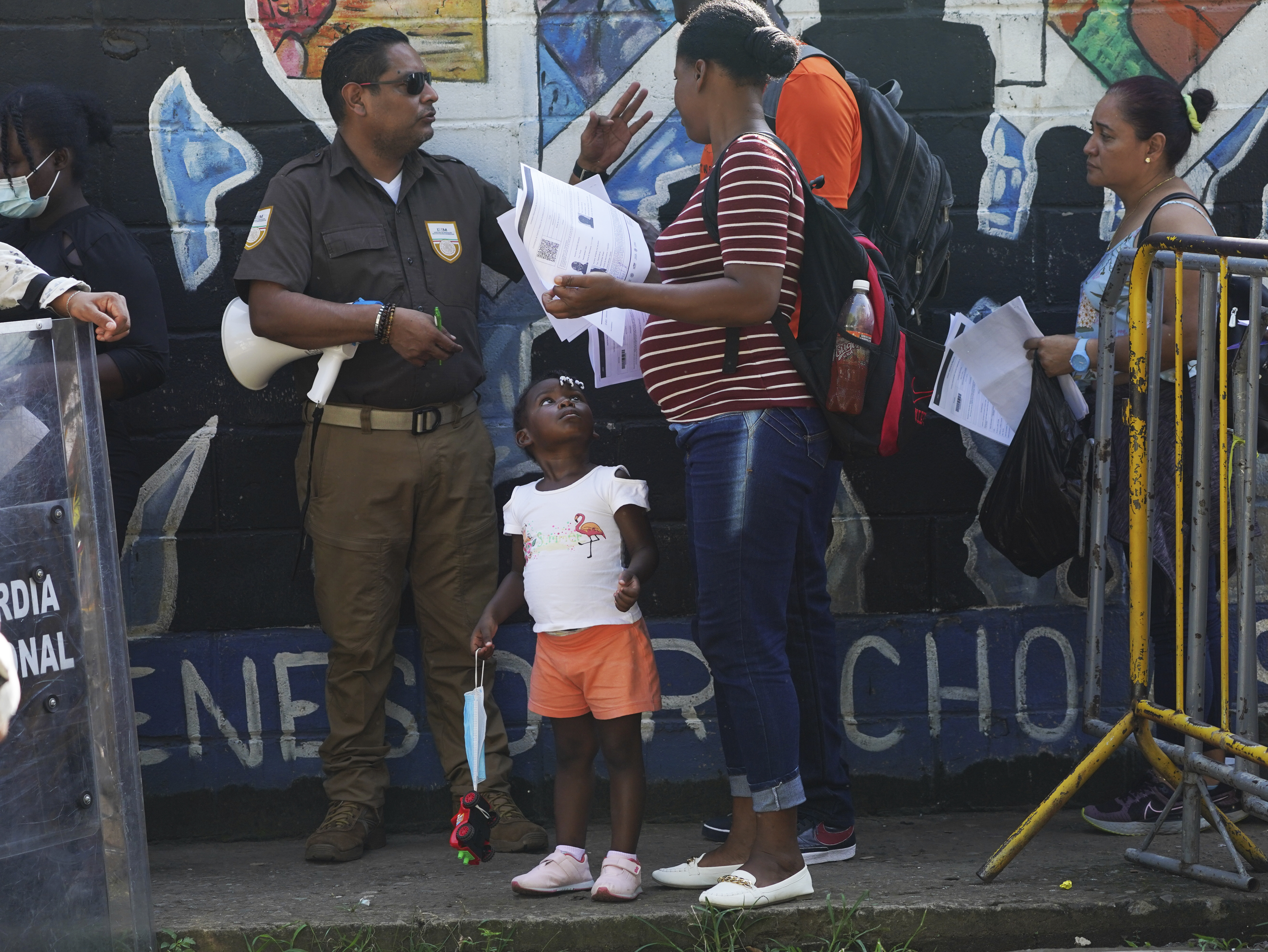A Mexican immigration officer checks the documents of migrants waiting in line to apply for legal migration papers