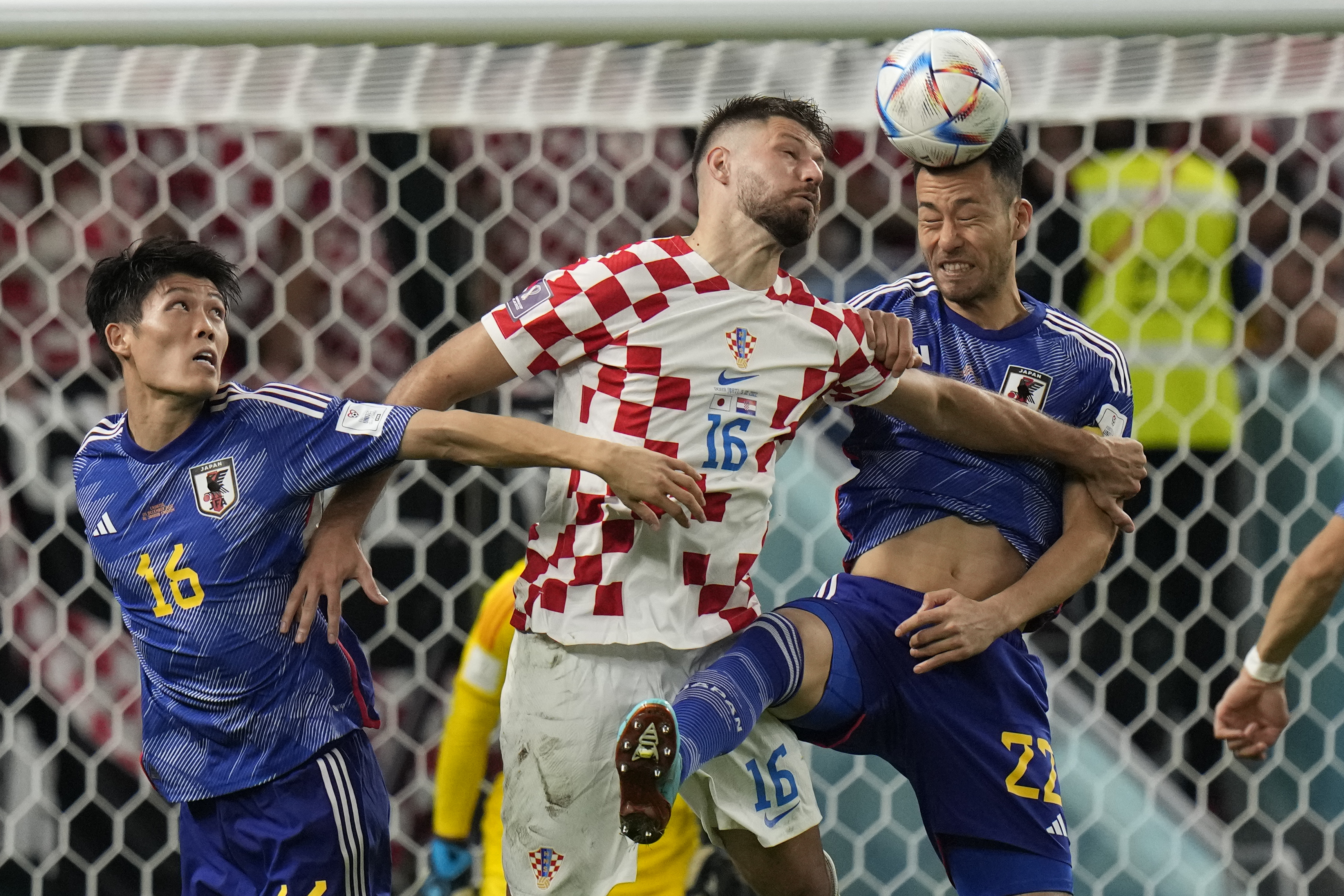 Japan's Maya Yoshida fights to head the ball with Croatia's Bruno Petkovic while Japan's Takehiro Tomiyasu looks on.