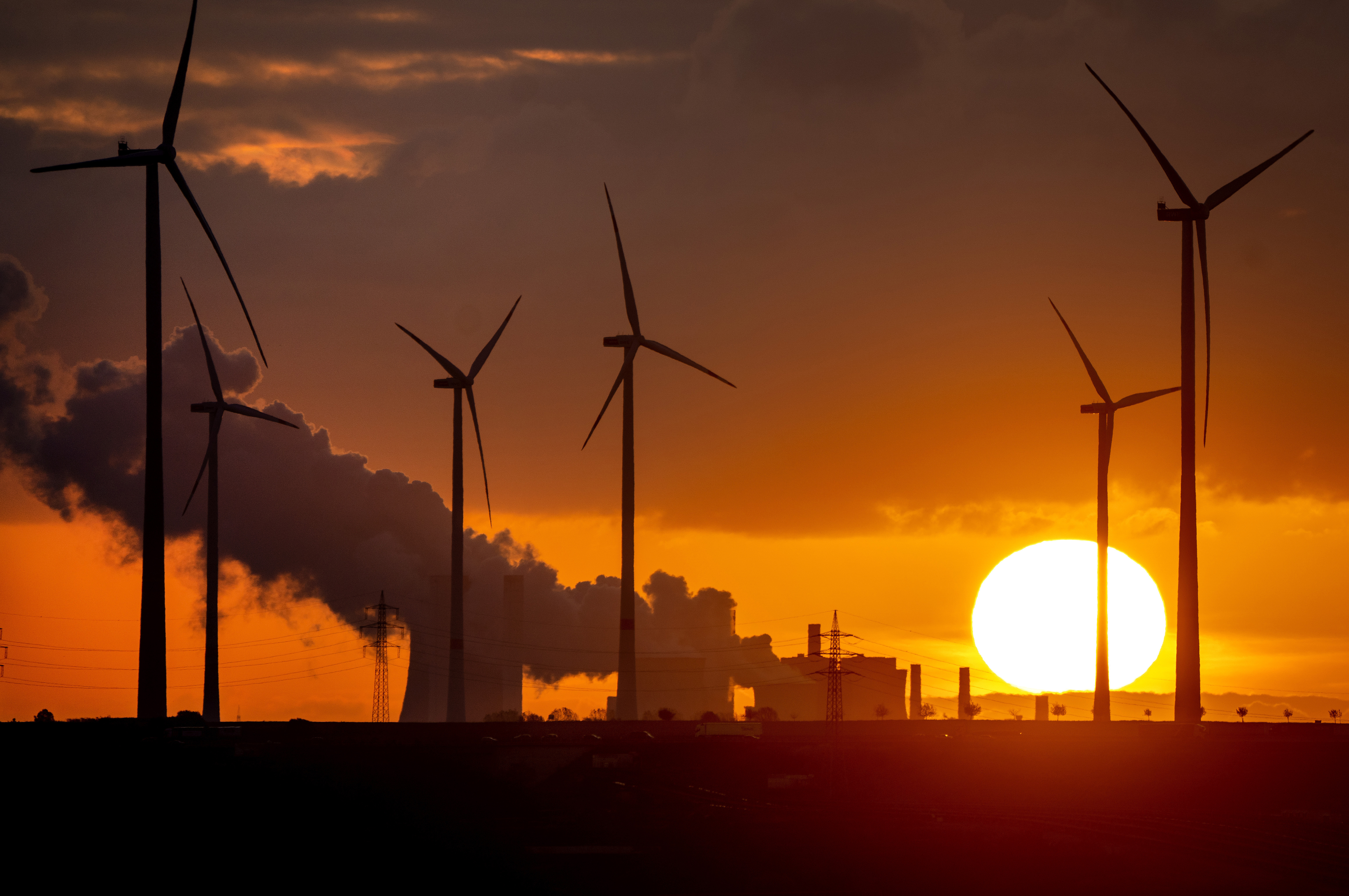 Steam rises from the coal-fired power plant near wind turbines