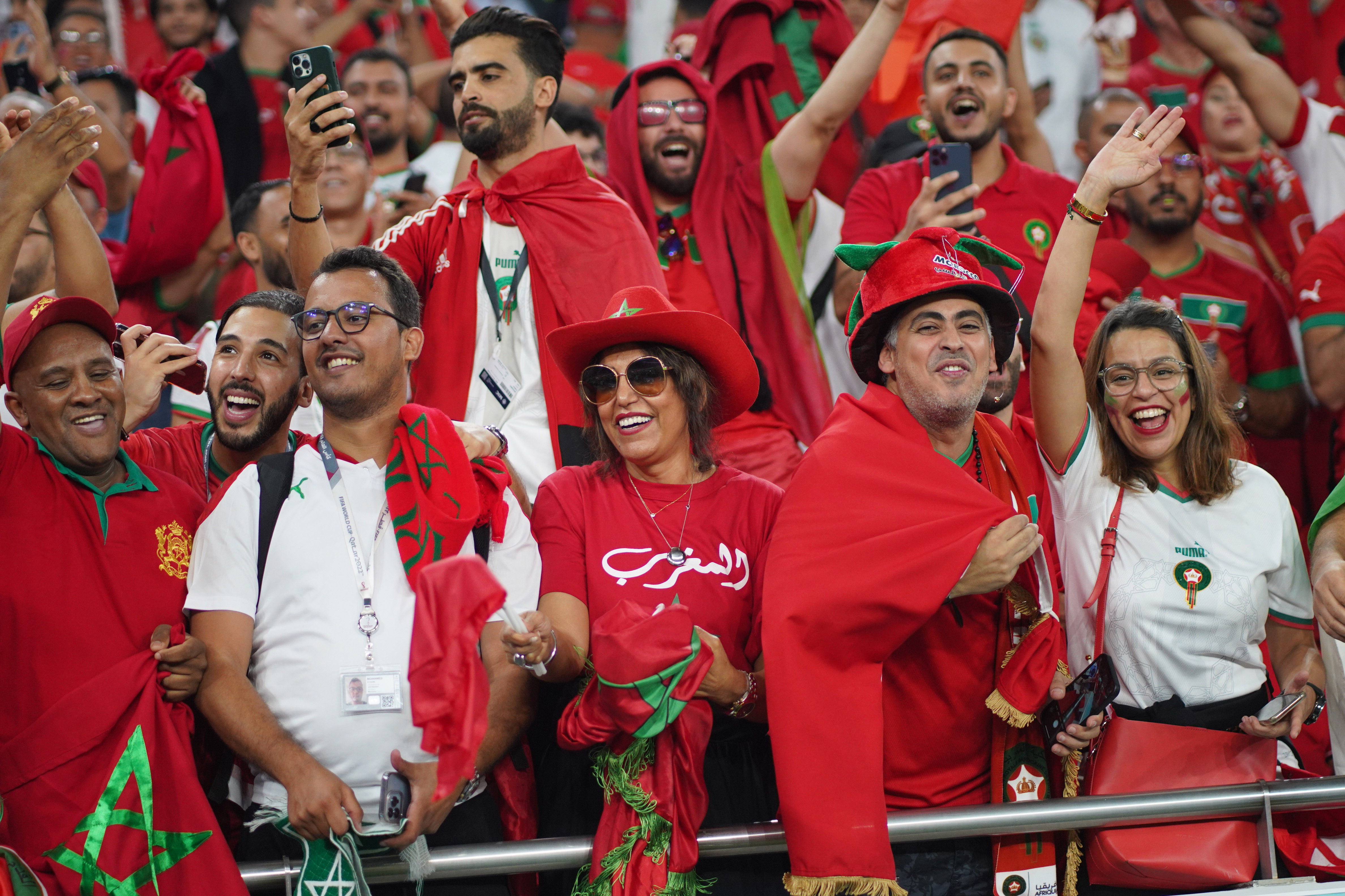 Morocco fans all in red with some green shimmering looking very happy