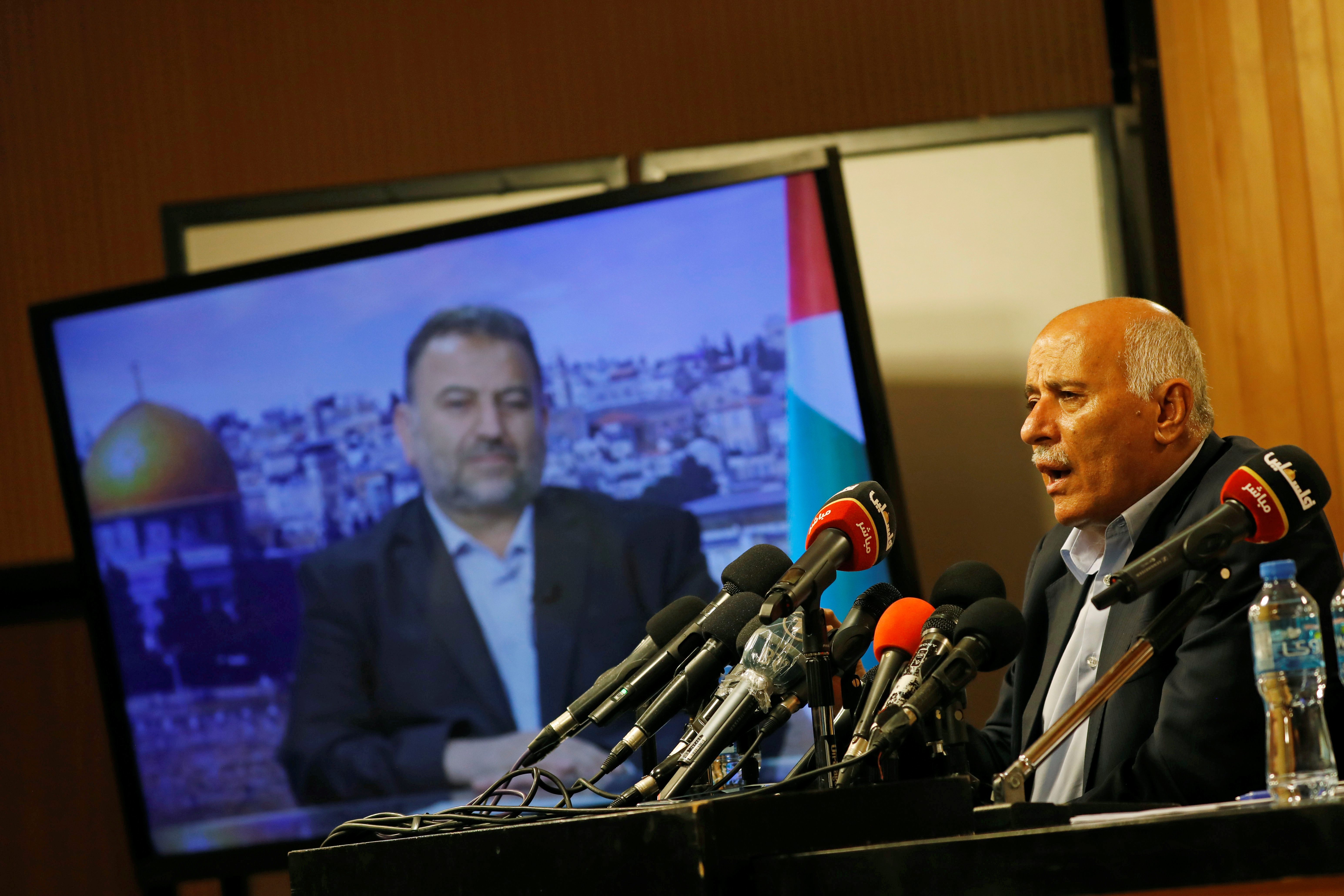 Senior Fatah official Jibril Rajoub speaks as deputy Hamas chief Saleh Arouri appears on a television screen during a video conference to discuss Israel's plan to annex parts of the Israeli-occupied West Bank, in Ramallah July 2, 2020. REUTERS/Mohamad Torokman