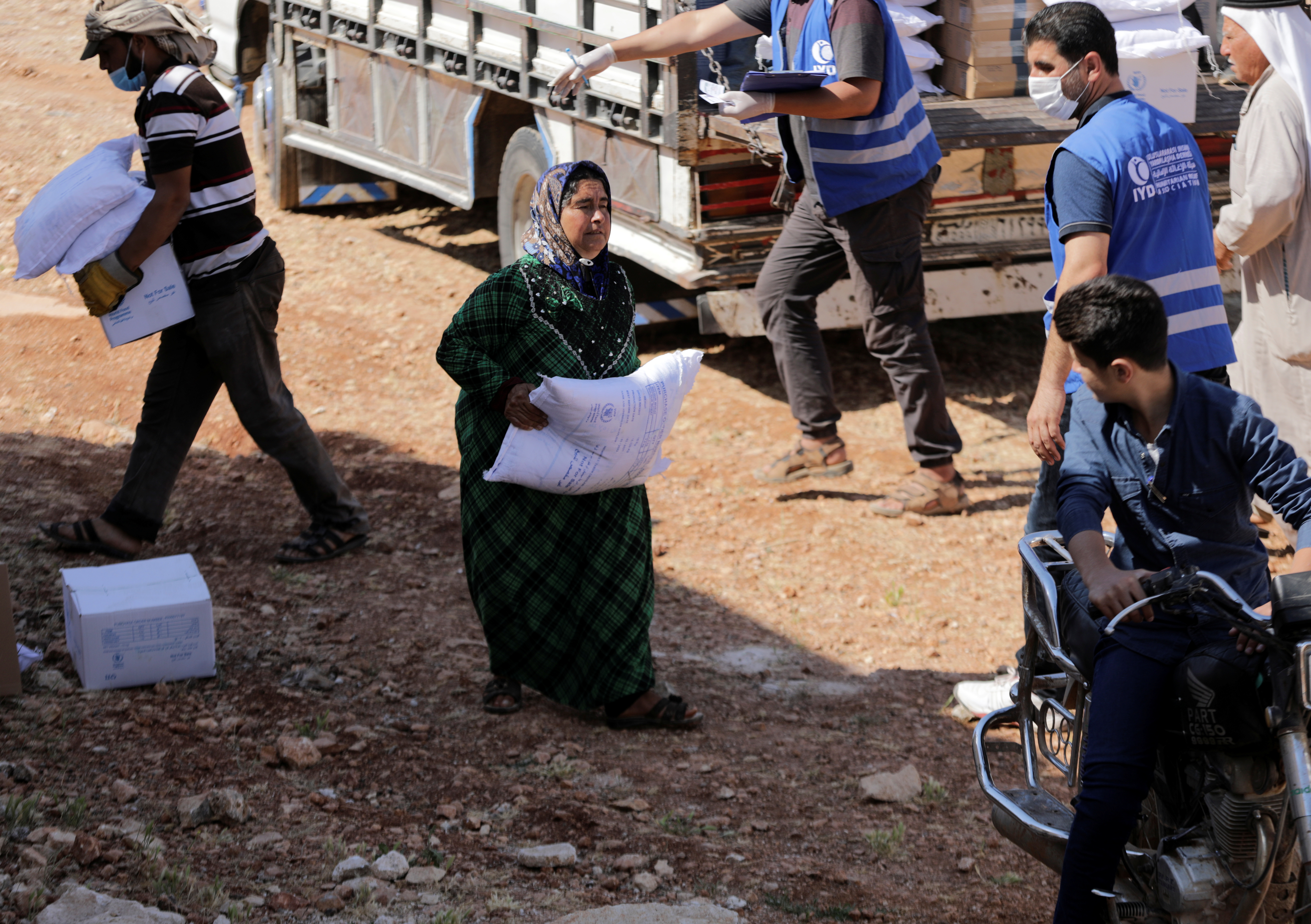 An internally displaced Syrian woman walks as she holds a bag of humanitarian aid in the opposition-held Idlib, Syria