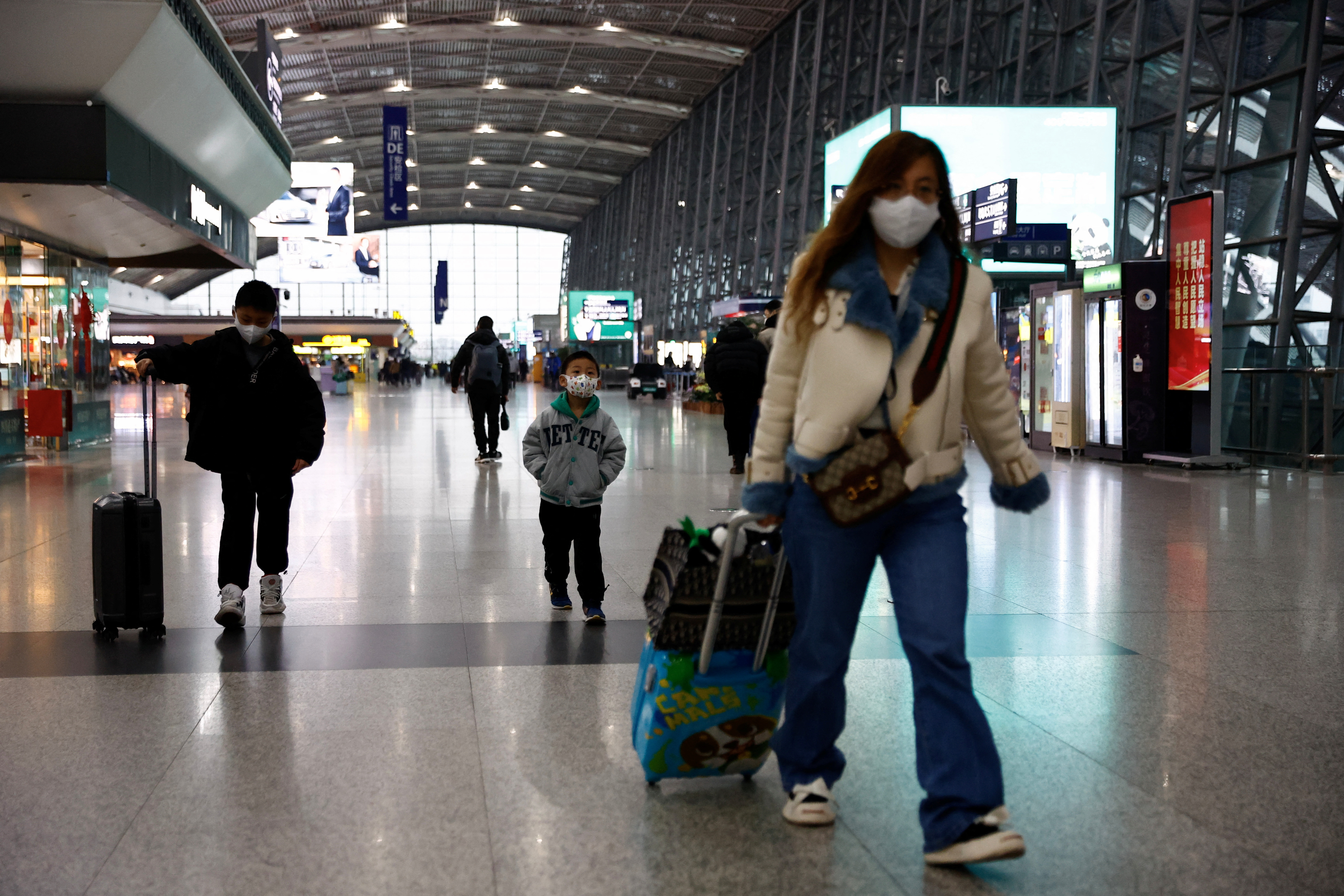 Travellers walk with their luggage at Chengdu Shuangliu International Airport in Chengdu, Sichuan province, China