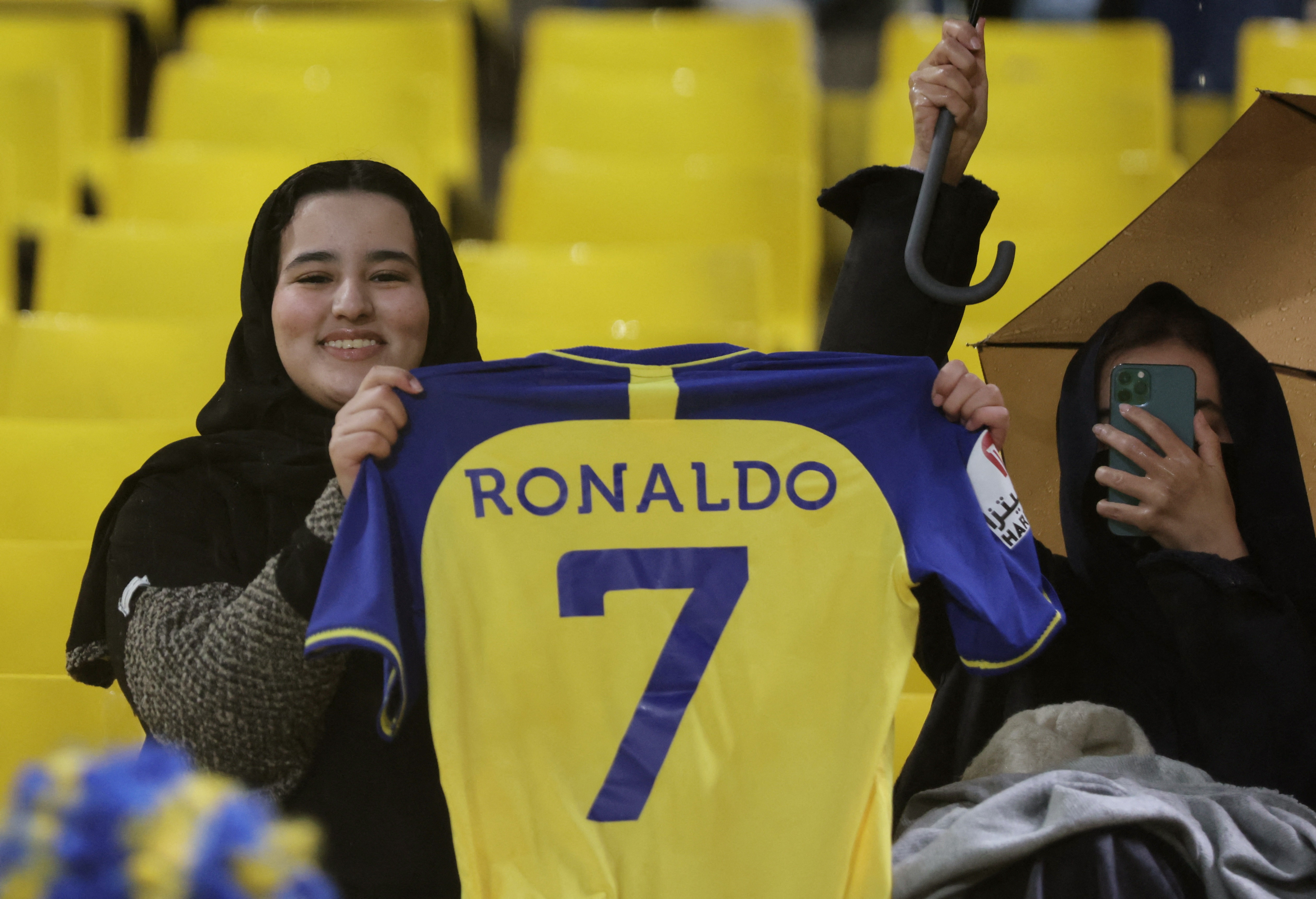 Soccer Football - Saudi Pro League - Al Nassr v Al Tai - Mrsool Park, Riyadh, Saudi Arabia - January 6, 2023 An Al Nassr fan poses holding a shirt with Cristiano Ronaldo's name on the back of it inside the stadium before the match REUTERS/Ahmed Yosri