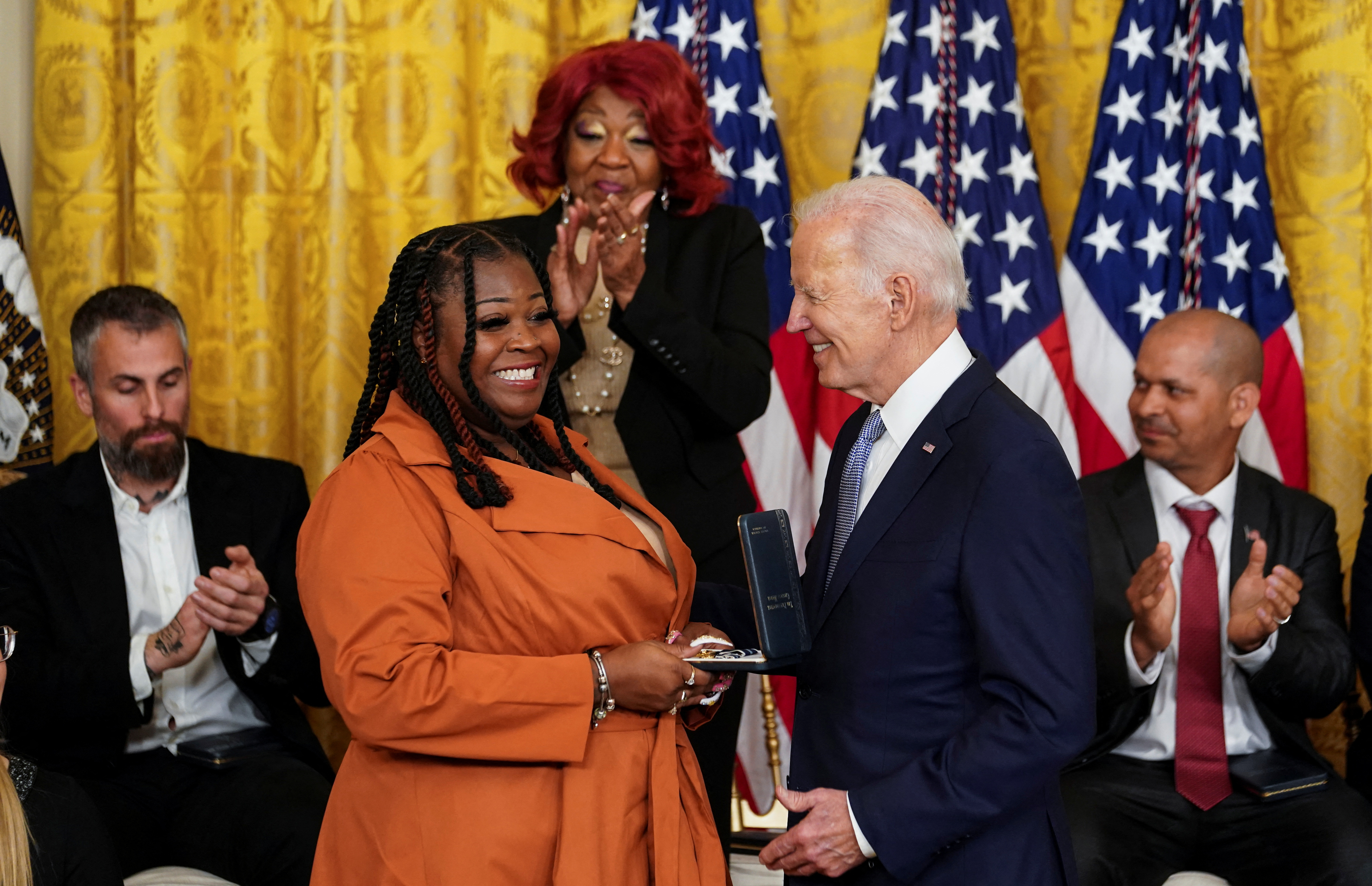 President Joe Biden hands Shaye Moss a medal as her mother applauds