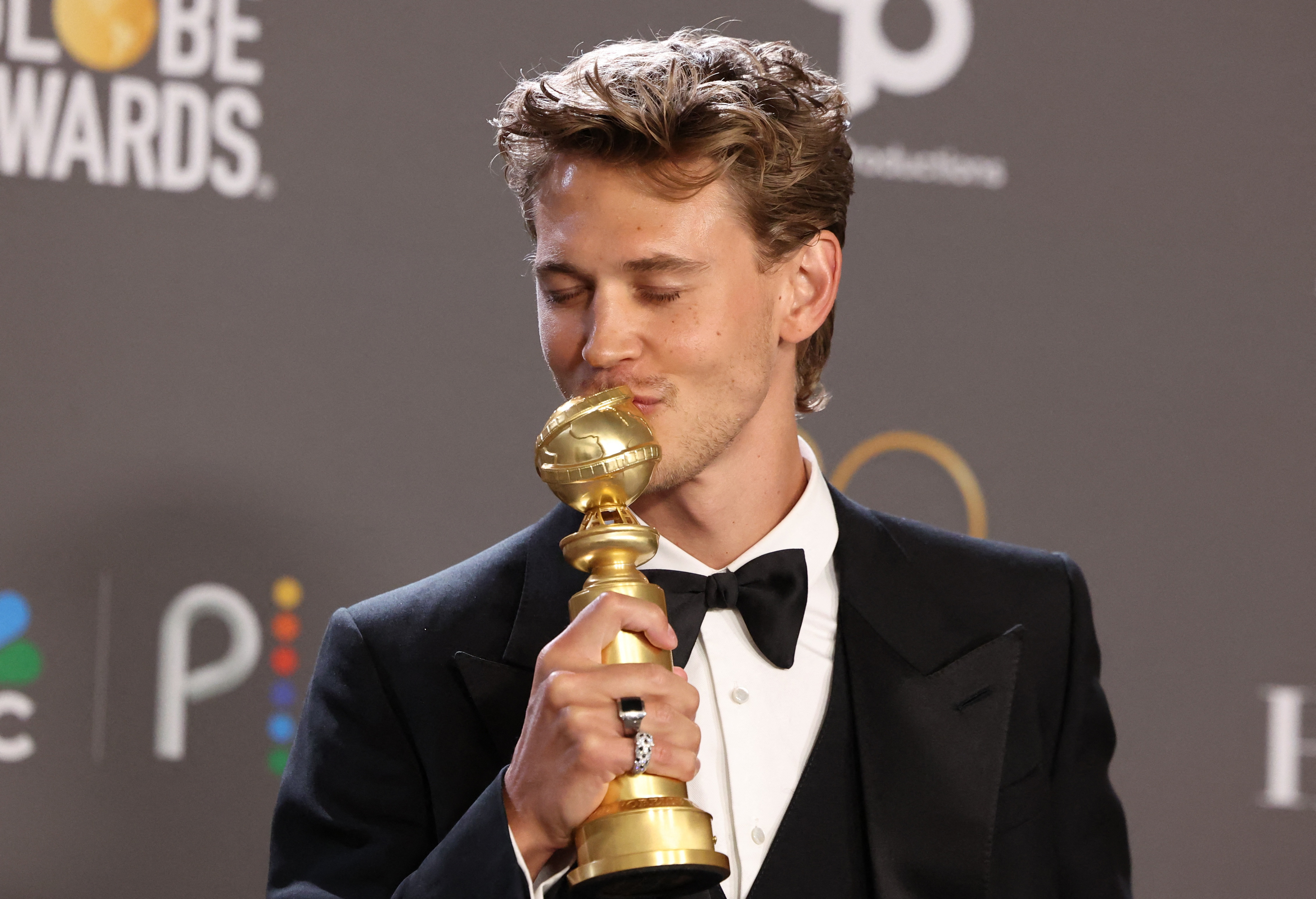 Austin Butler in a tuxedo kissing his Golden Globe. He looks very happy