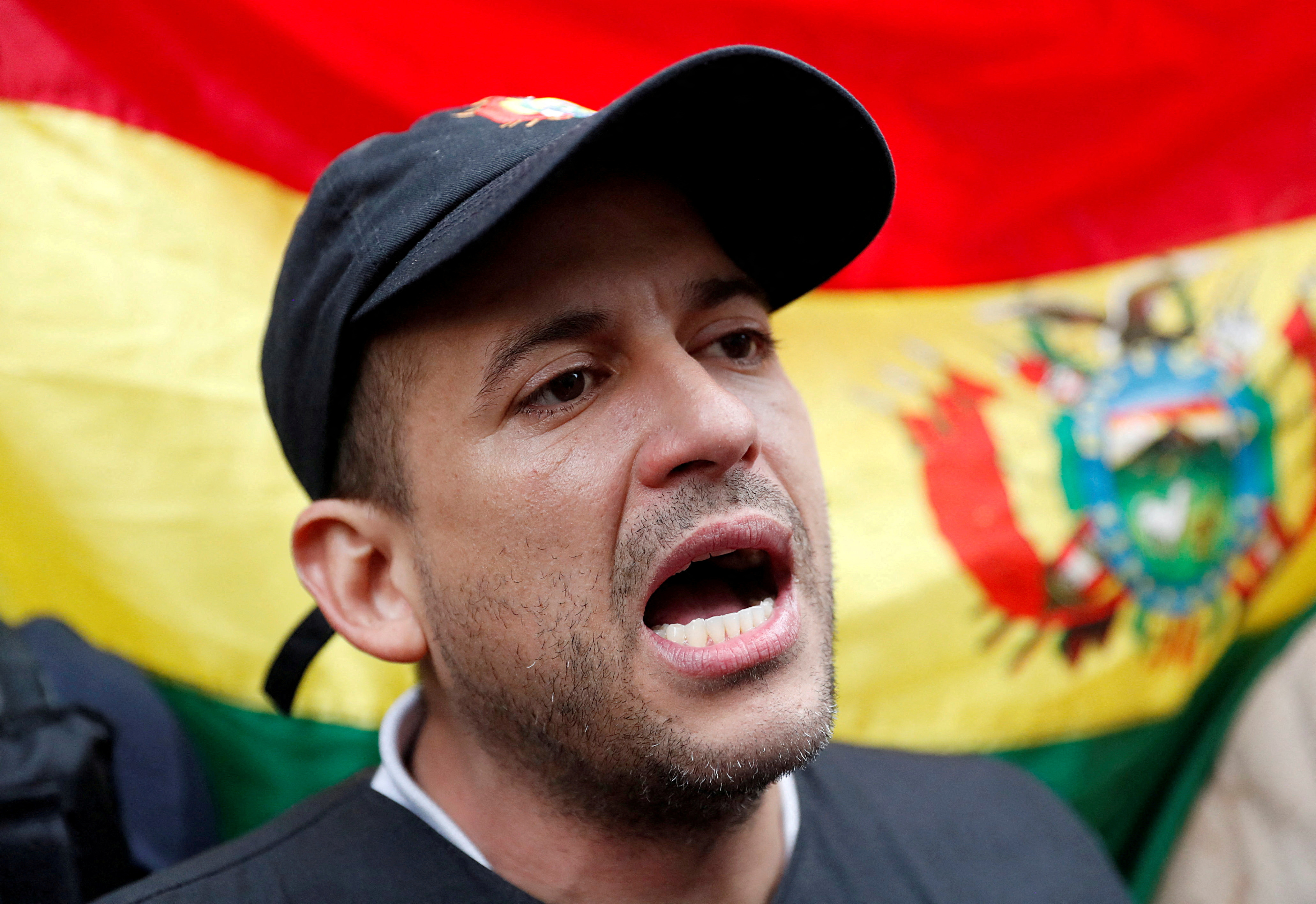Luis Fernando Camacho speaks against the backdrop of a flag