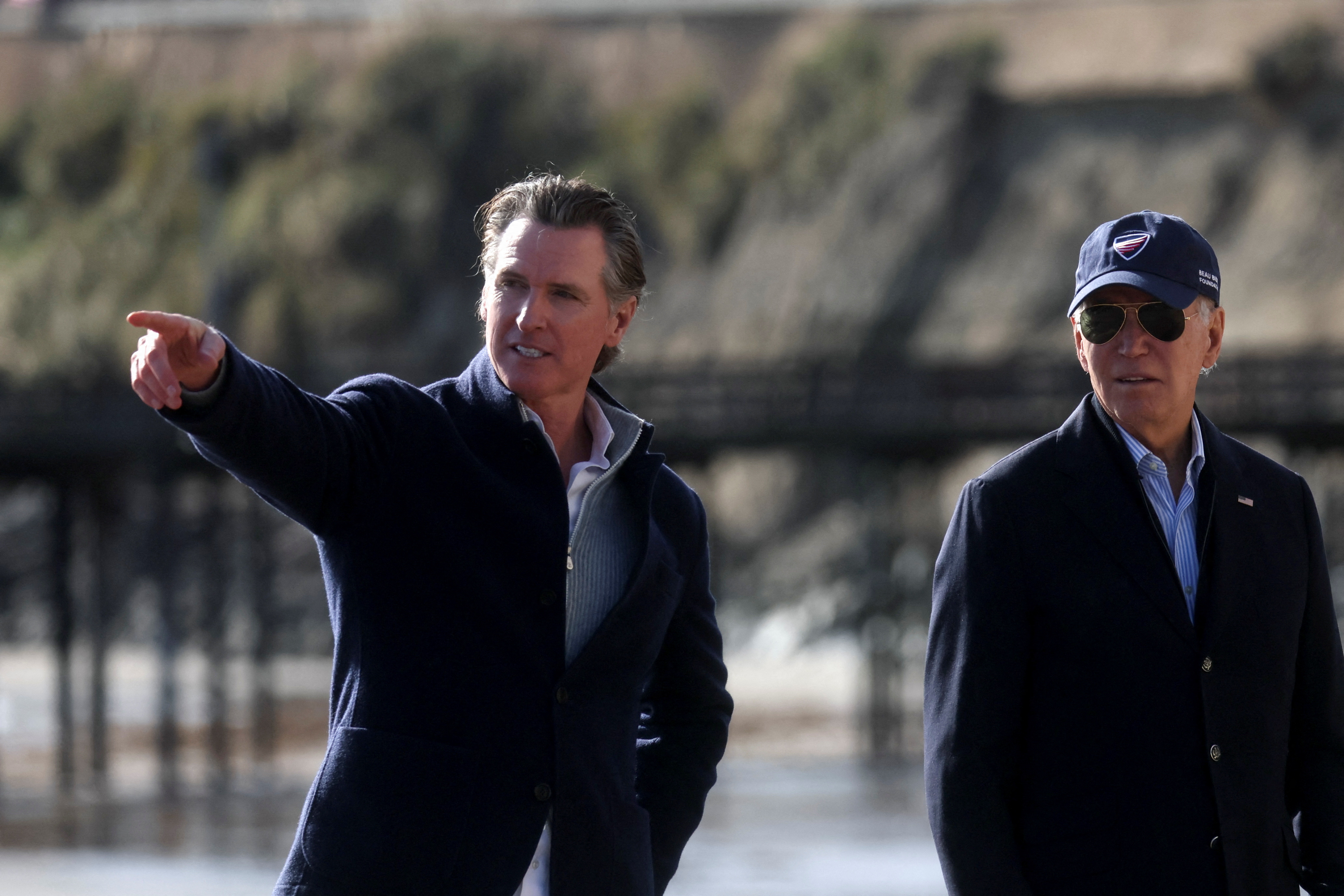 US President Biden looks on at storm damage alongside California Governor Gavin Newsom
