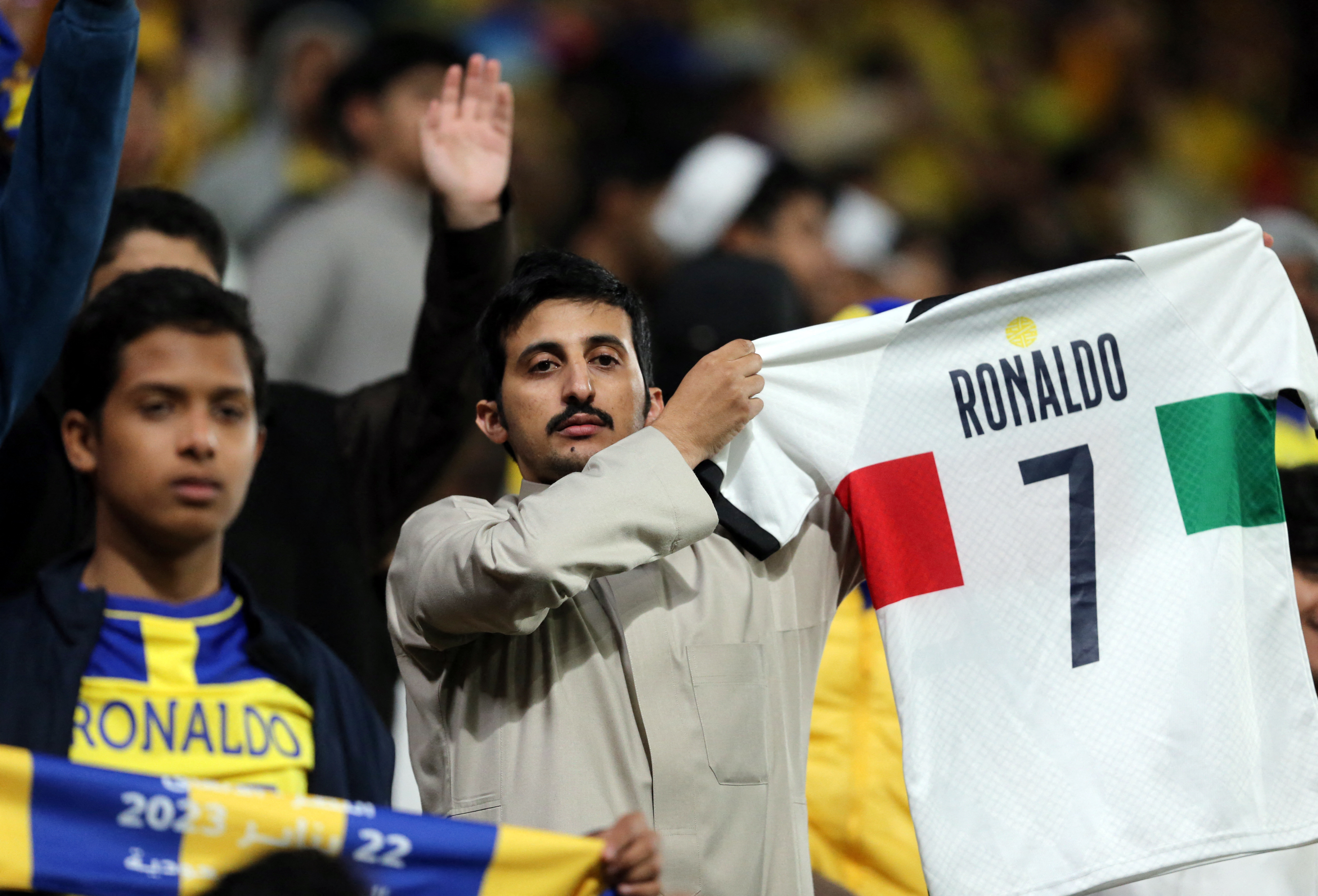 Soccer Football - Saudi Pro League - Al Nassr v Al Ettifaq - Mrsool Park, Riyadh, Saudi Arabia - January 22, 2023 An Al Nassr fan holds a Portugal shirt with Cristiano Ronaldo's name printed on the back during the match 
