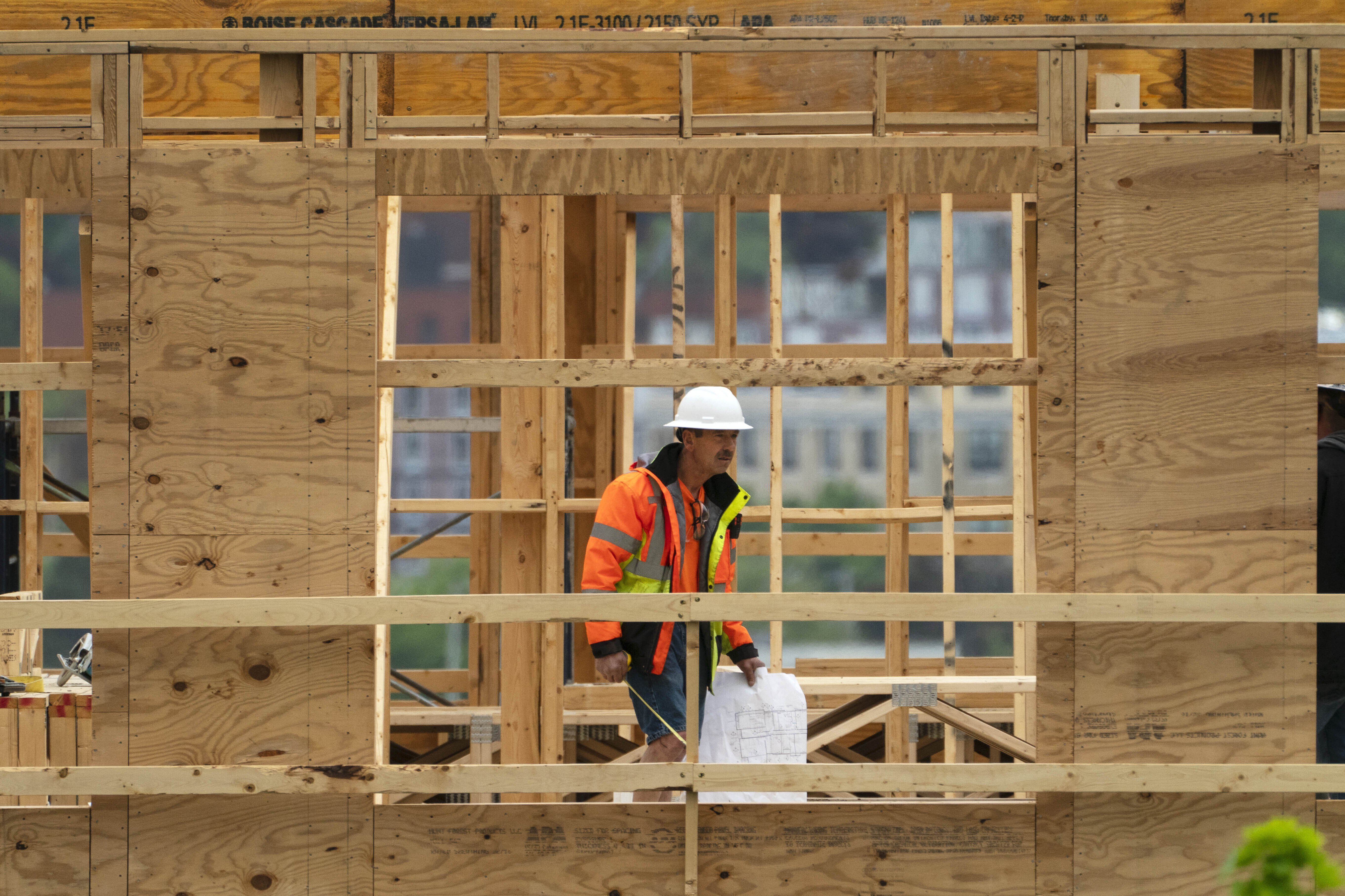 A worker with plans checks construction of a four-story, 45-unit condominium building in Portland, Maine, US
