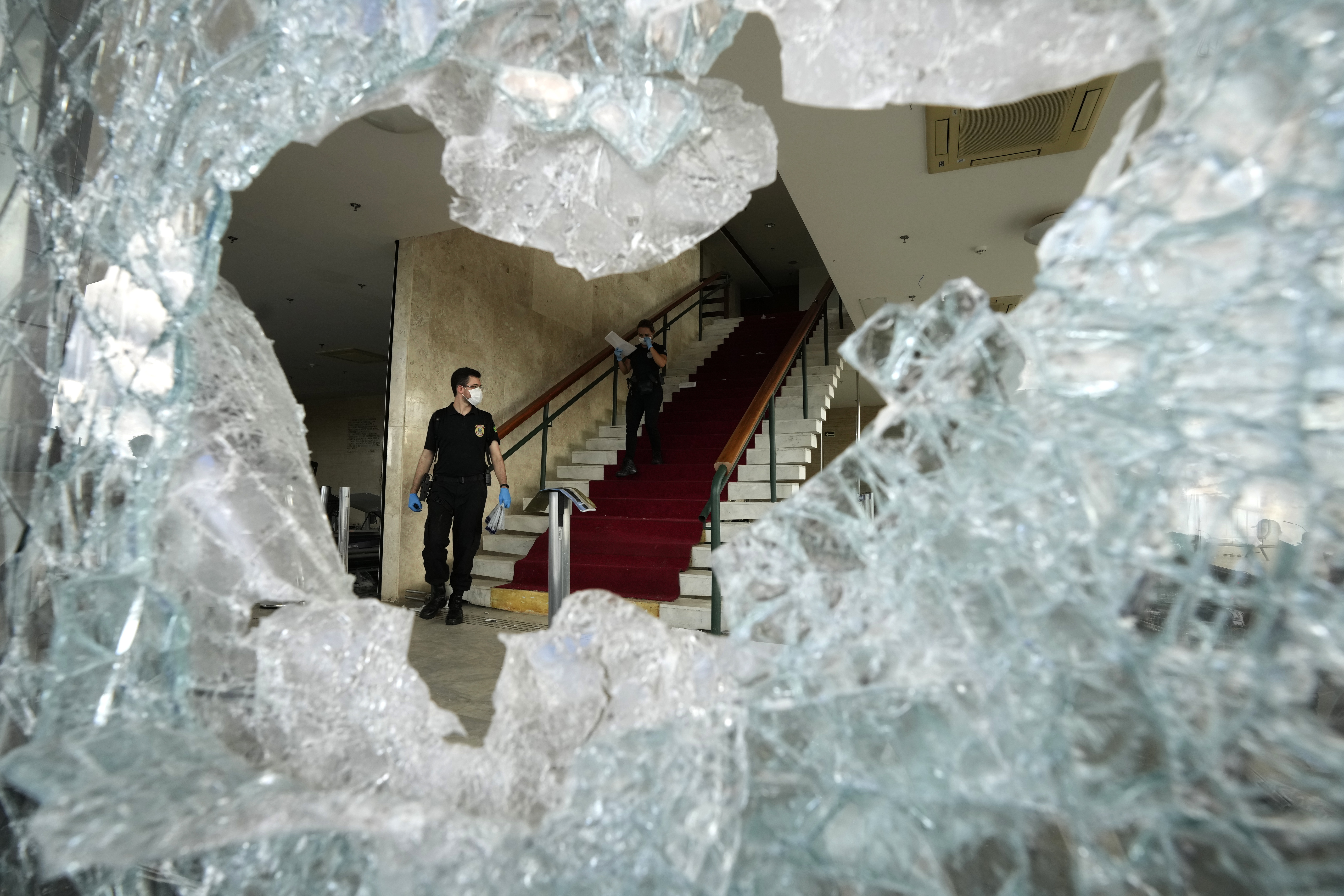 An investigator, seen through a hole in a shattered window