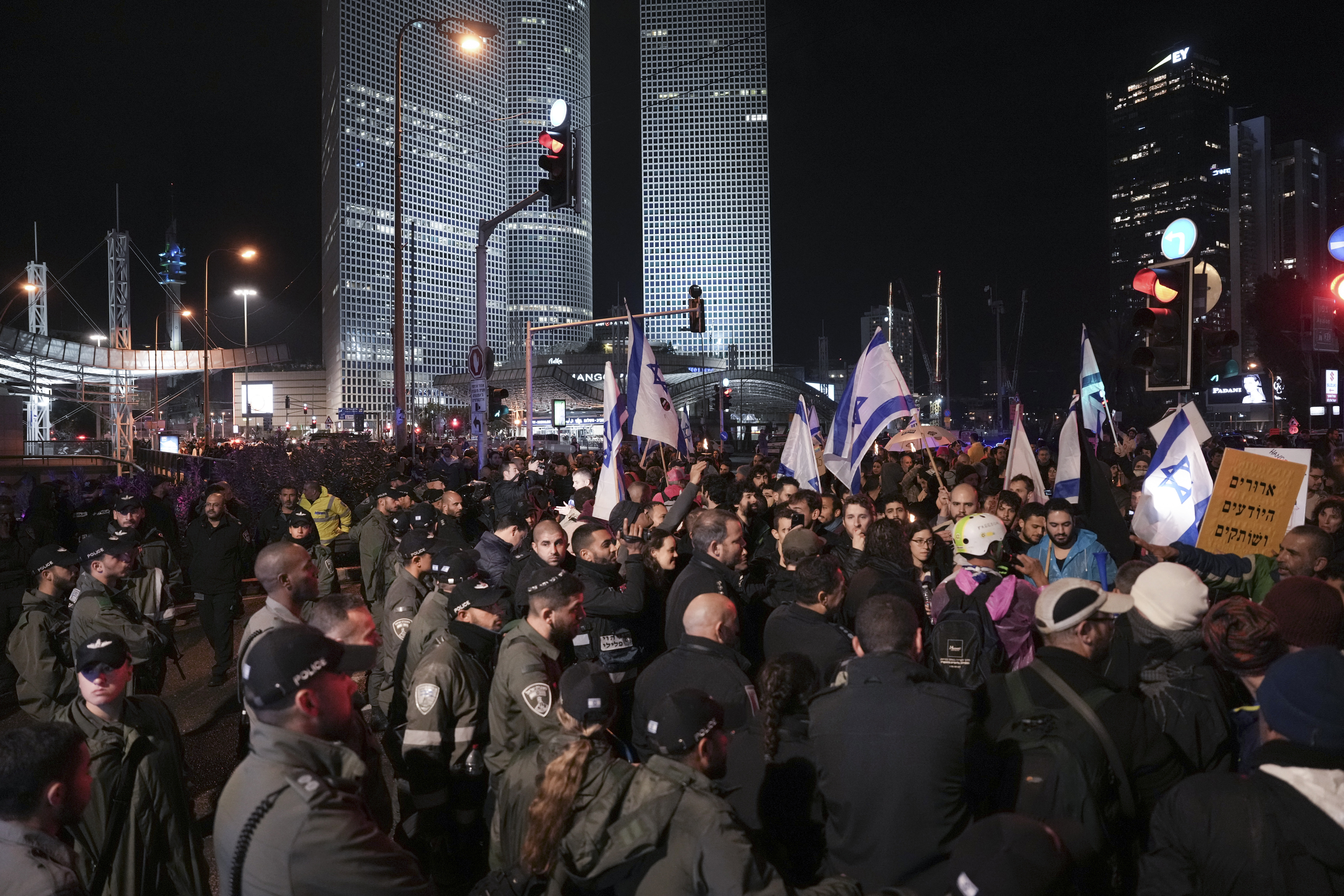 Israeli border police officers prevent protesters from blocking a highway during a rally against the government's plans to overhaul the country's legal system, in Tel Aviv, Israel, Saturday, Jan. 14, 2023. Tens of thousands of Israelis have gathered in central Tel Aviv to protest plans by Prime Minister Benjamin Netanyahu's new government to overhaul the country's legal system and weaken the Supreme Court. 