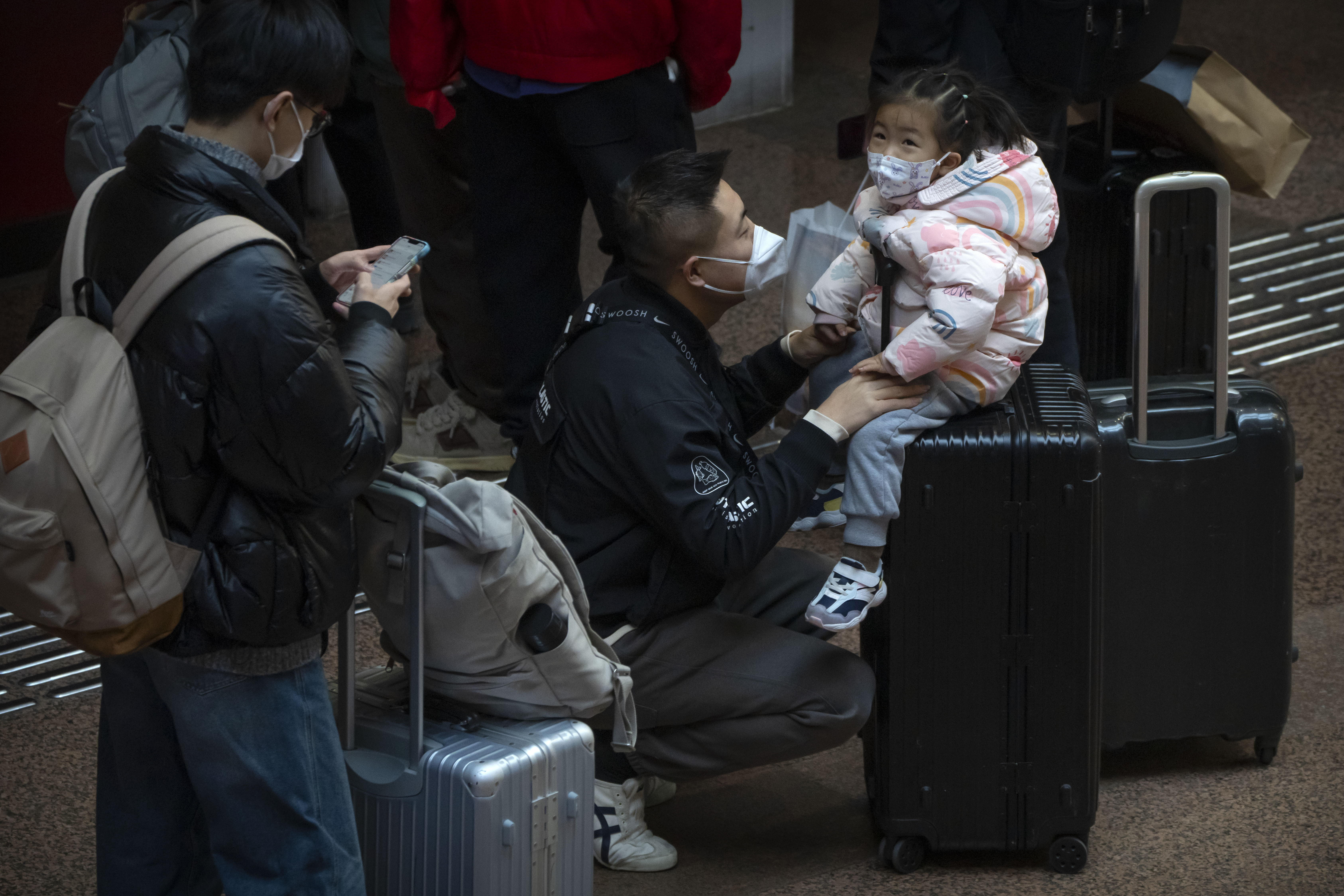 A child sits on a suitcase at Beijing West Railway Station in Beijing