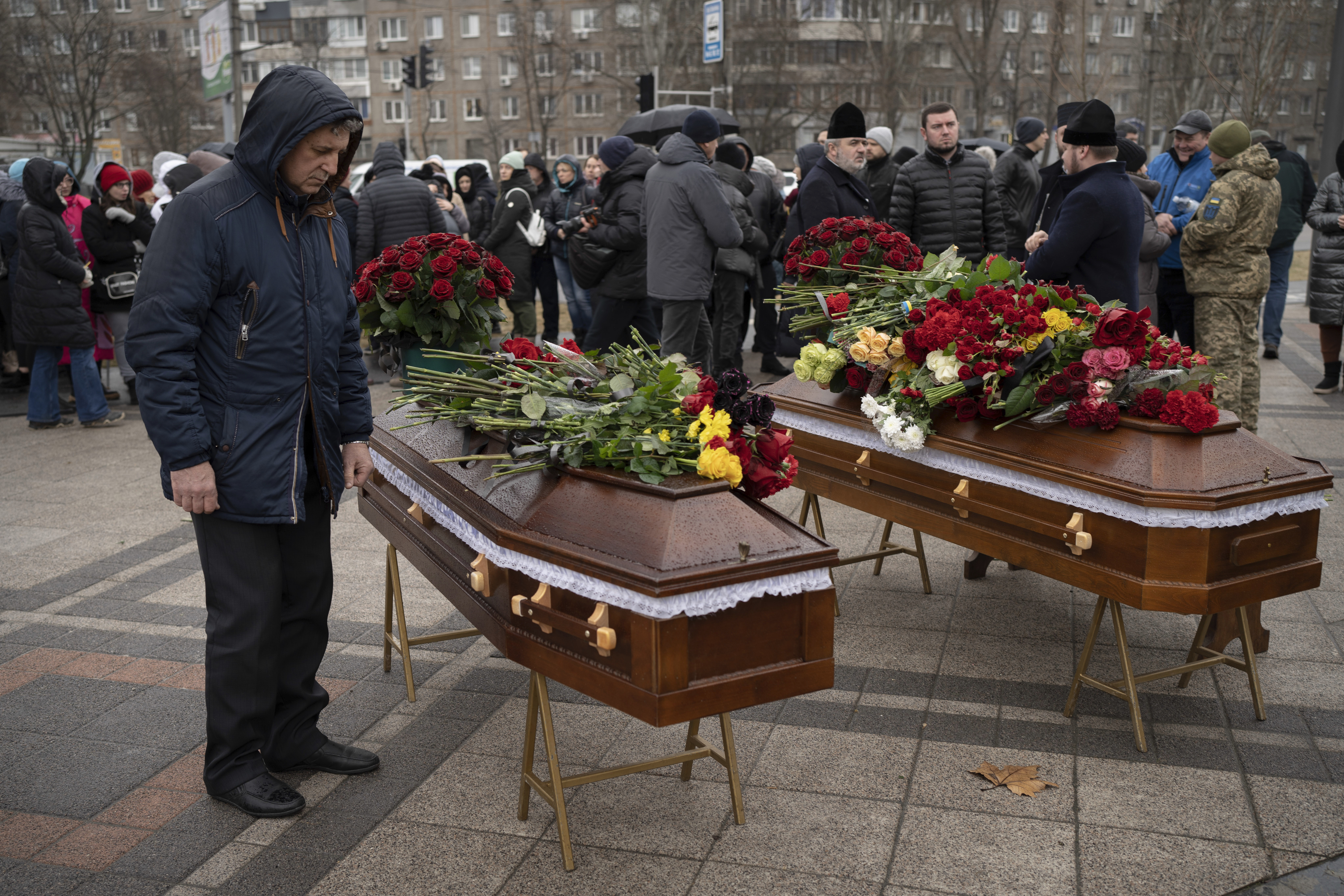 A relative of Maksym and Nataliia Shvets, a couple who died under the rubble after Russia hit their apartment block with a missile, mourns by the coffins during a funeral service in Dnipro, Ukraine