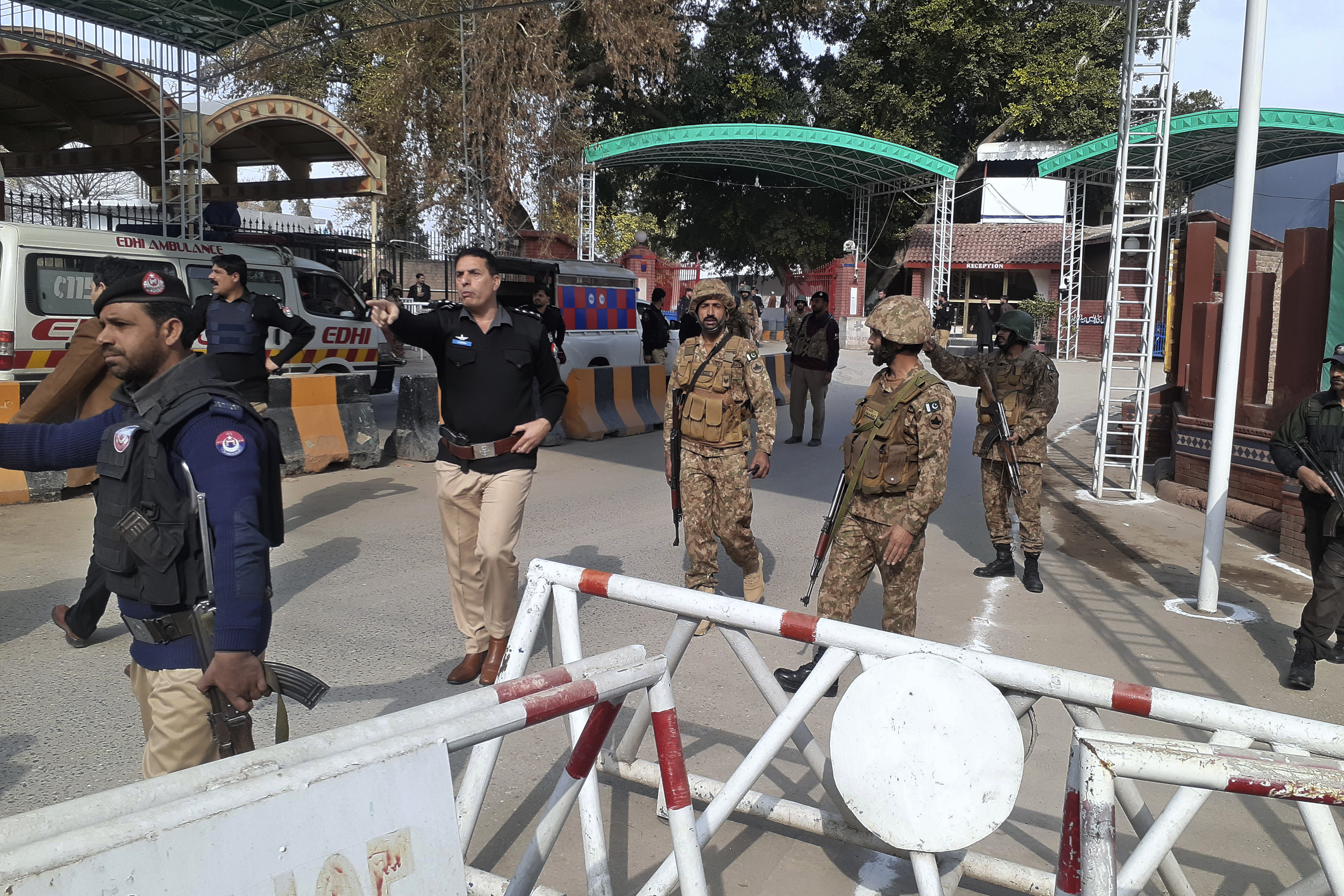 Army soldiers and police officers clear the way for ambulances rushing toward a bomb explosion site, at the main entry gate of police offices, in Peshawar, Pakistan