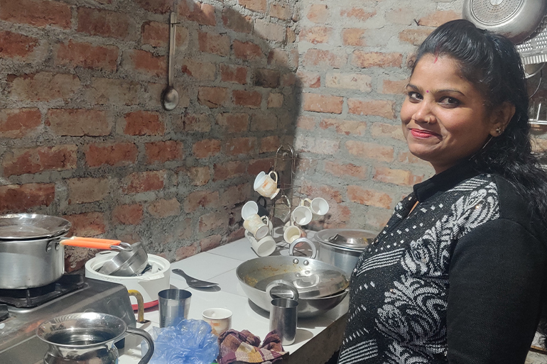 A photo of a woman standing in front of a stove.