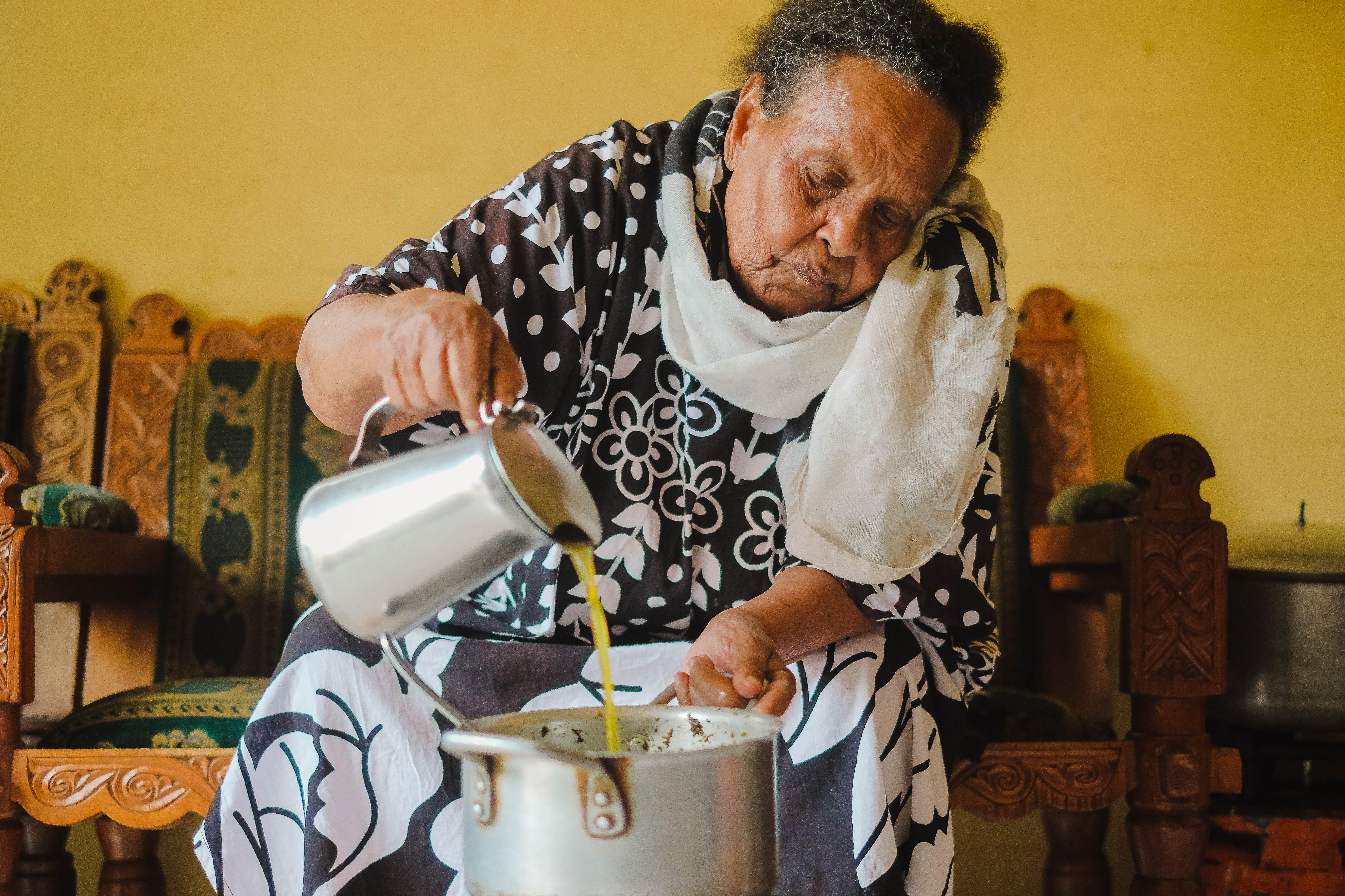 Bekelech adds niter kibe as a finishing touch to a pot of gomen kitfo