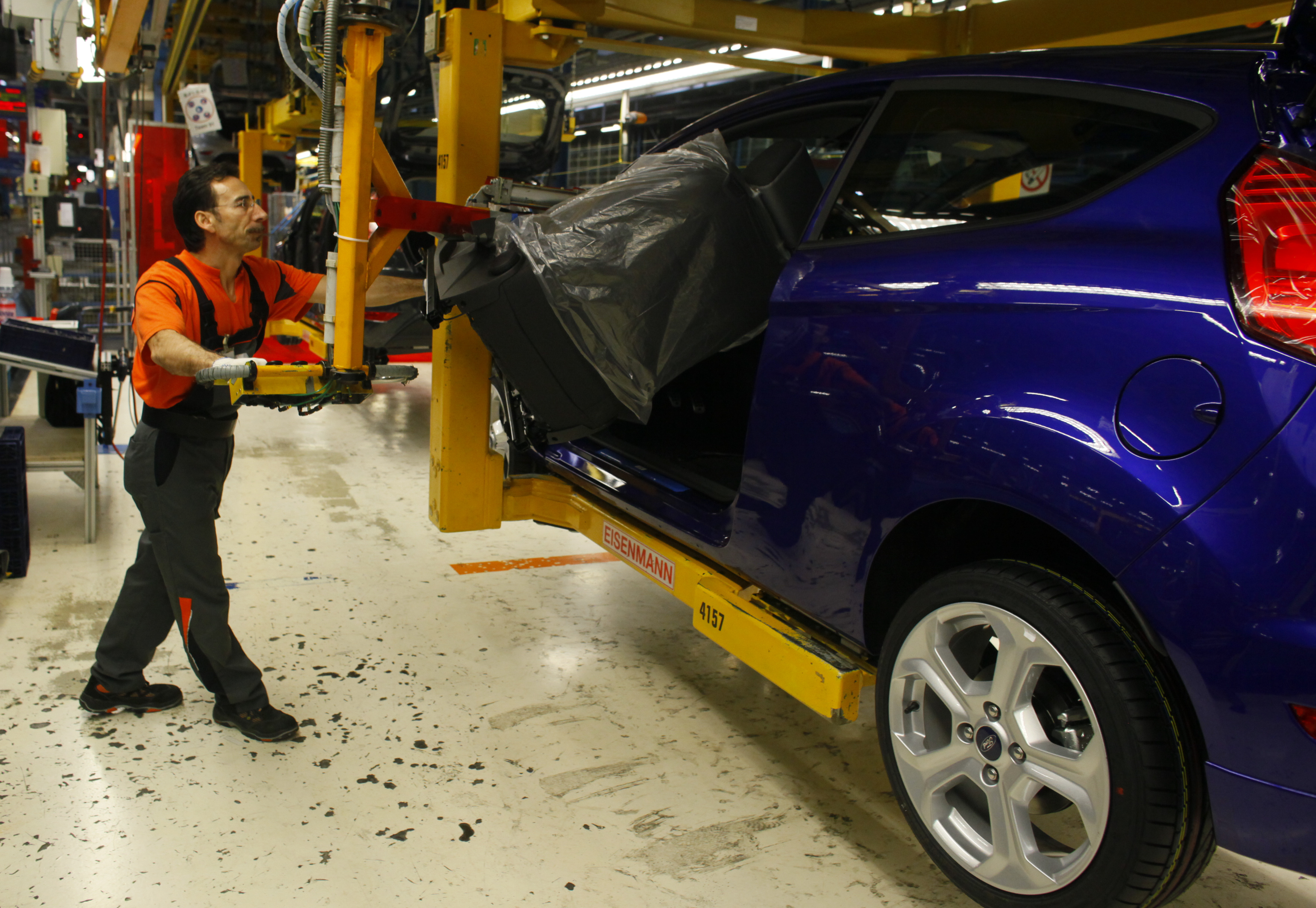 A worker mounts a seat inside a Fiesta ST at the Fiesta assembly line of Ford Germany in Cologne