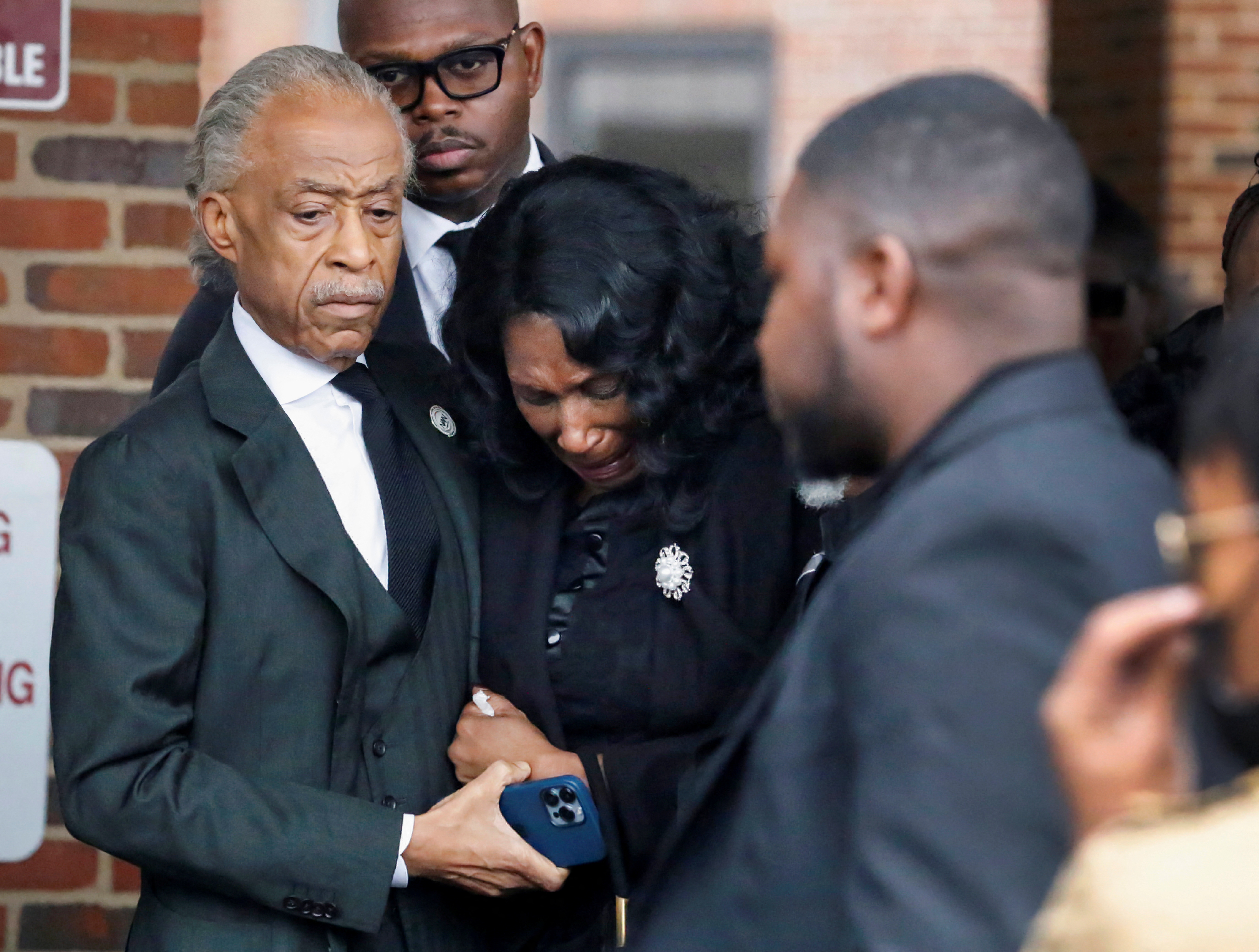 RowVaughn Wells and Al Sharpton holds Nichols's mother's hand as she leans forward with her head down, weeping