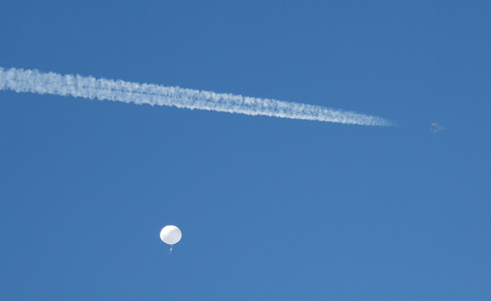 A jet flies by a suspected Chinese spy balloon as it floats off the coast in Surfside Beach, South Carolina