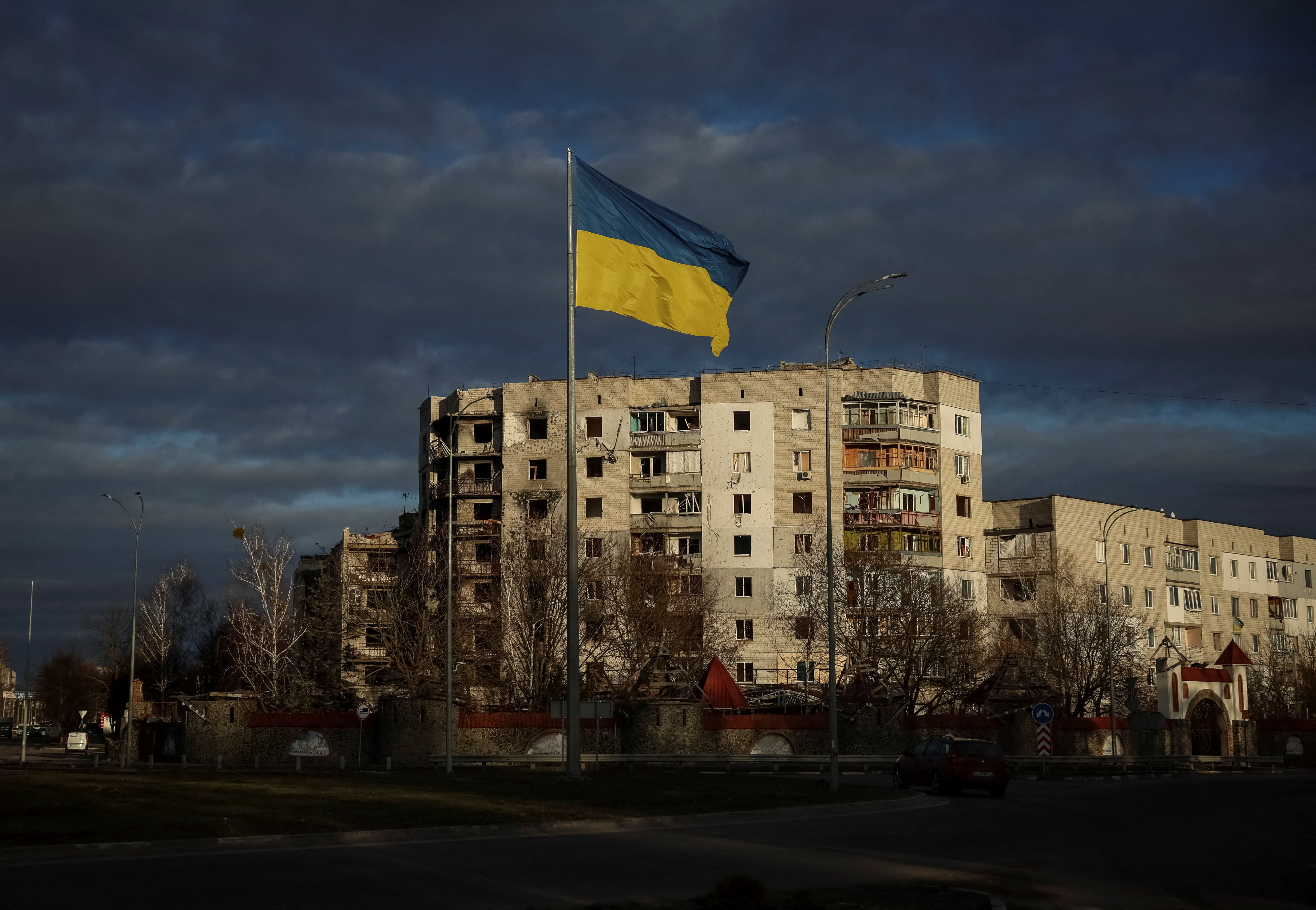 A Ukrainian national flag flutters near the buildings destroyed by Russian military attack in Kyiv