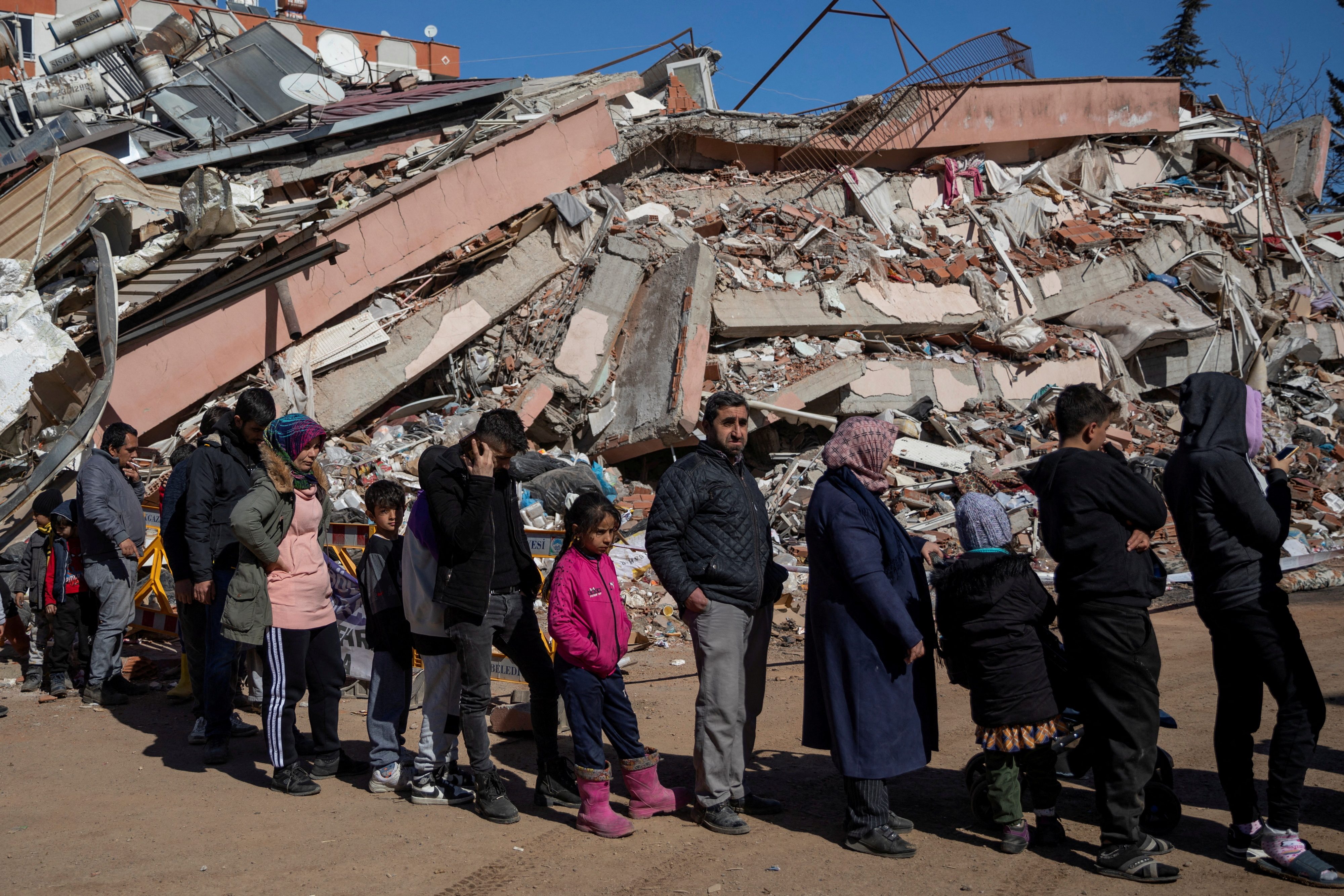 People queuing in front of a pancaked building for food