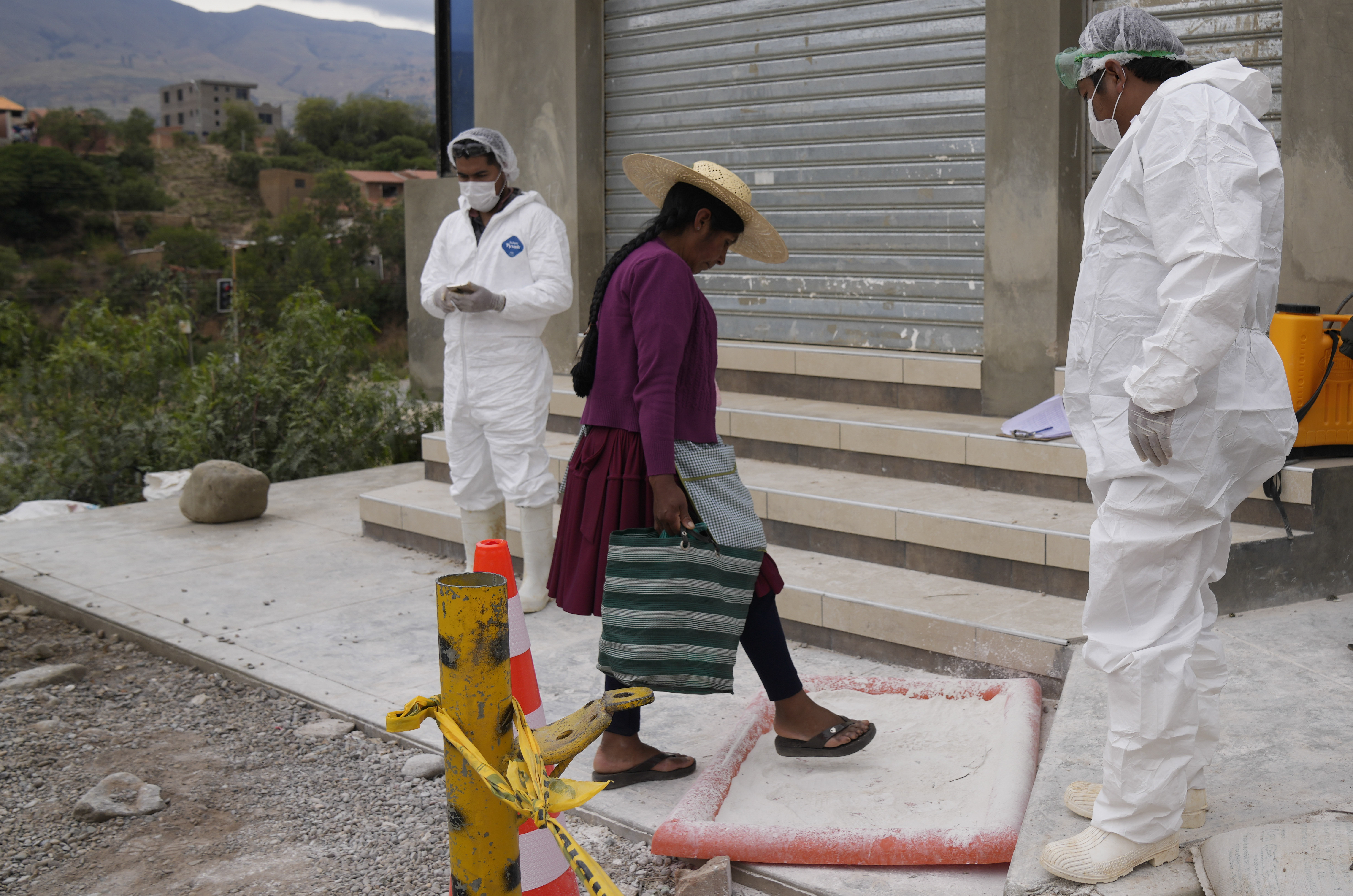 A woman steps on lime, set up by health workers who created a sanatation perimeter near chicken farms, as she walks home amid a health alert due to a bird flu outbreak in Sacaba, Bolivia.