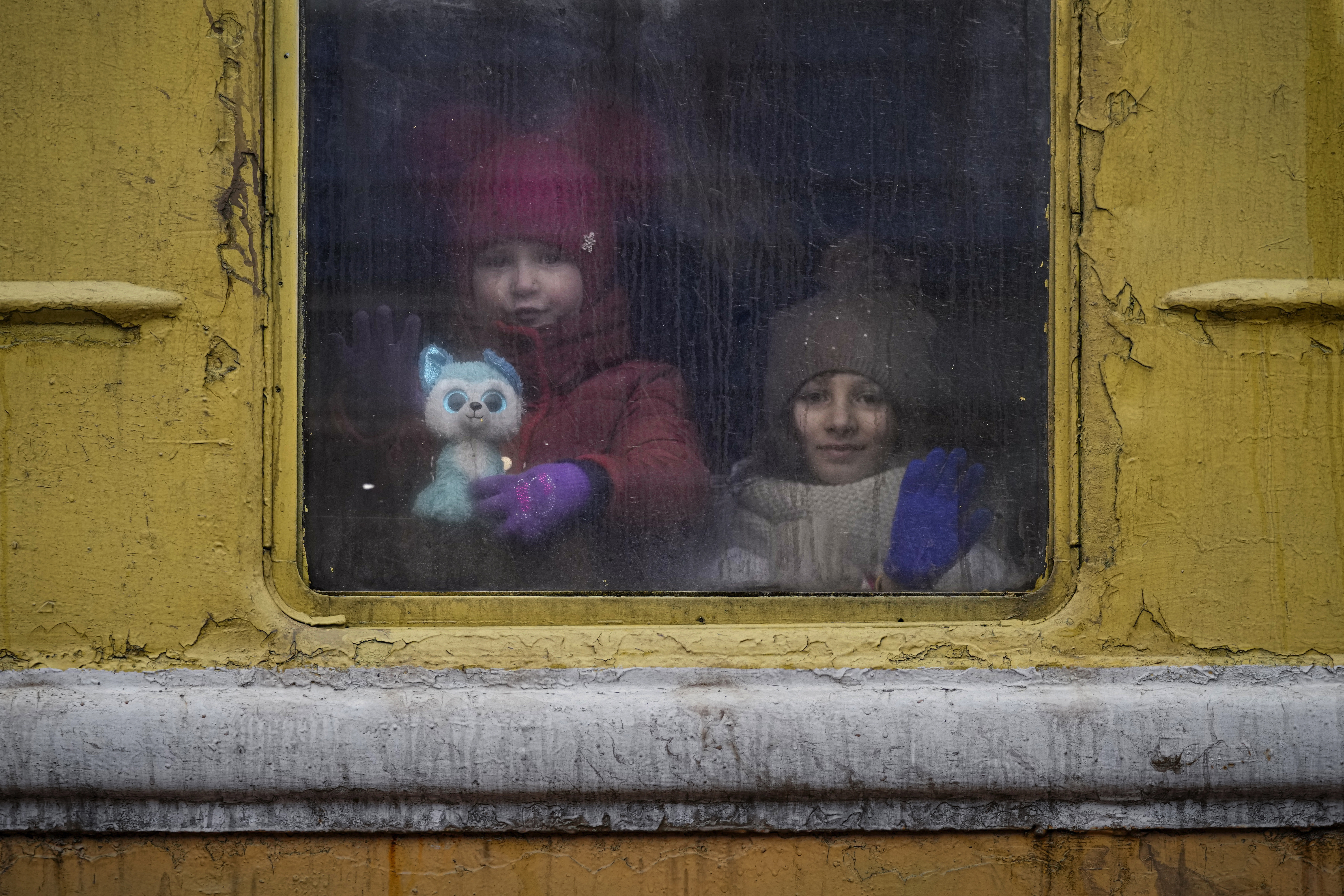 Children look out of the window of an unheated Lviv-bound train, in Kyiv