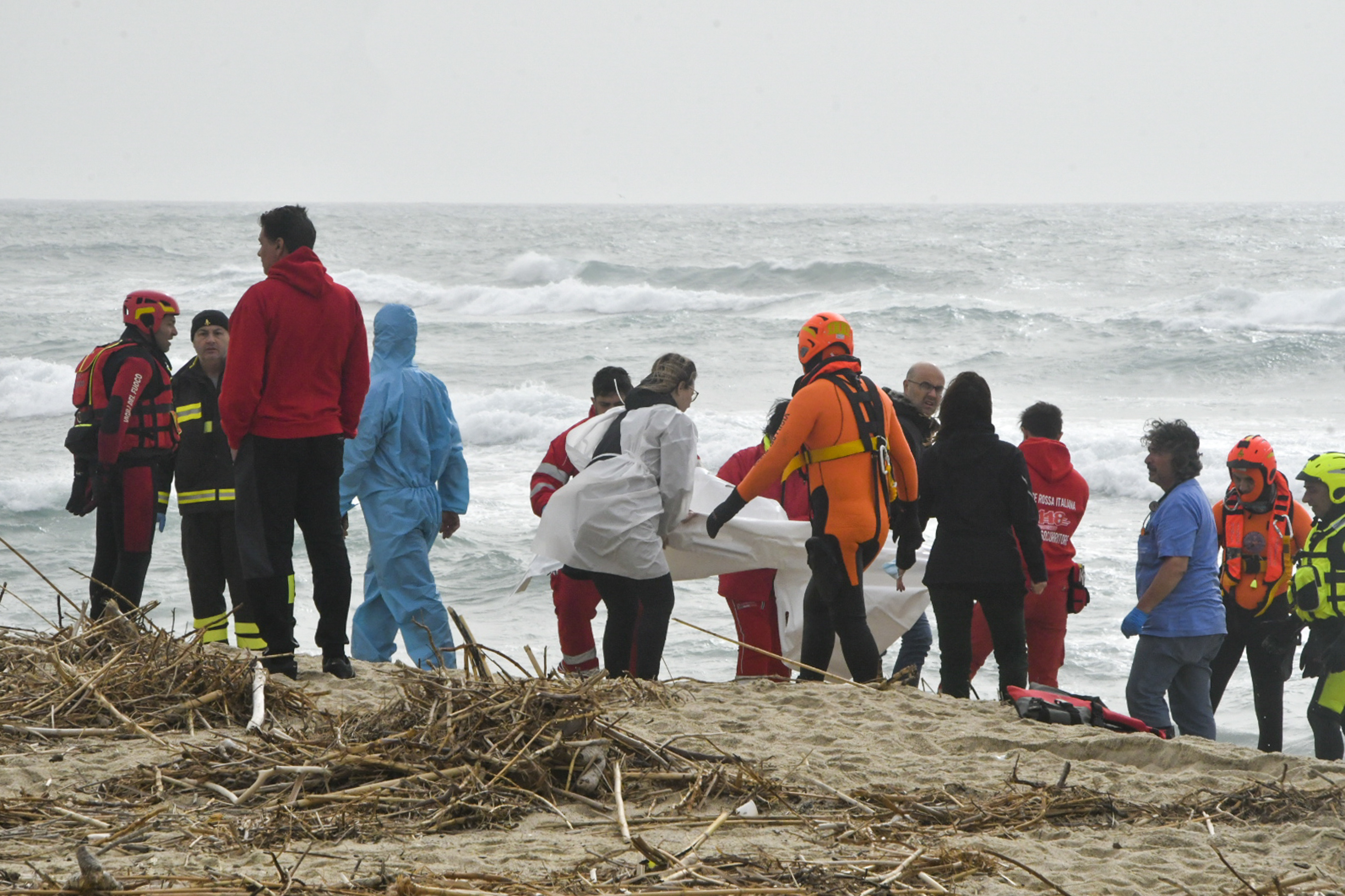 Rescuers recover a body at a beach near Cutro, southern Italy, after a migrant boat broke apart in rough seas