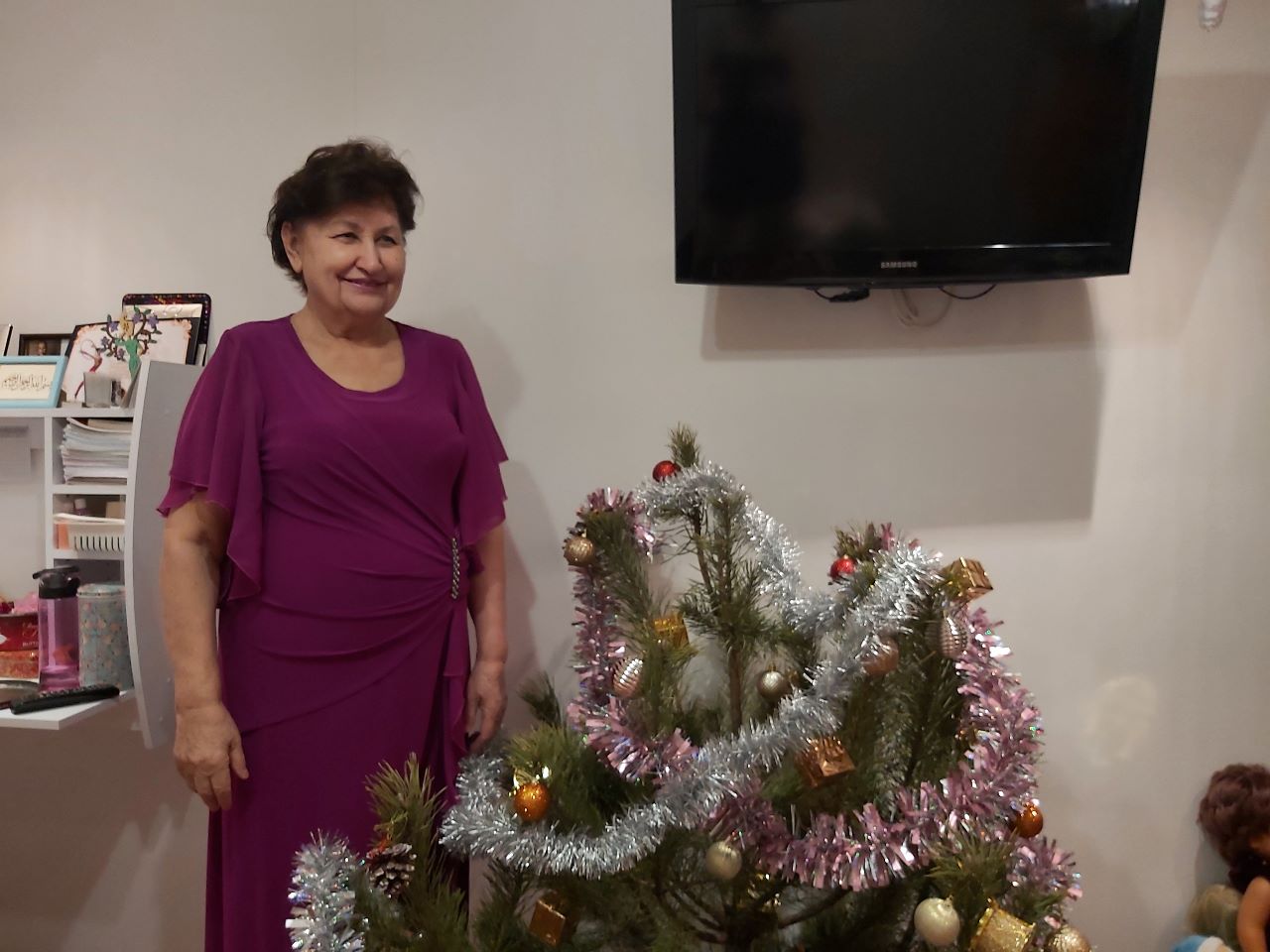 A photo of Abibe standing next to a decorated Christmas tree,