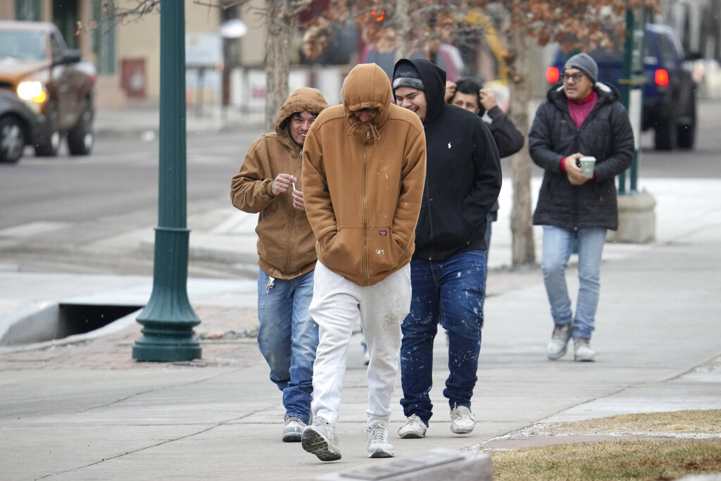 Pedestrians try to stay warm as they walk down the street 