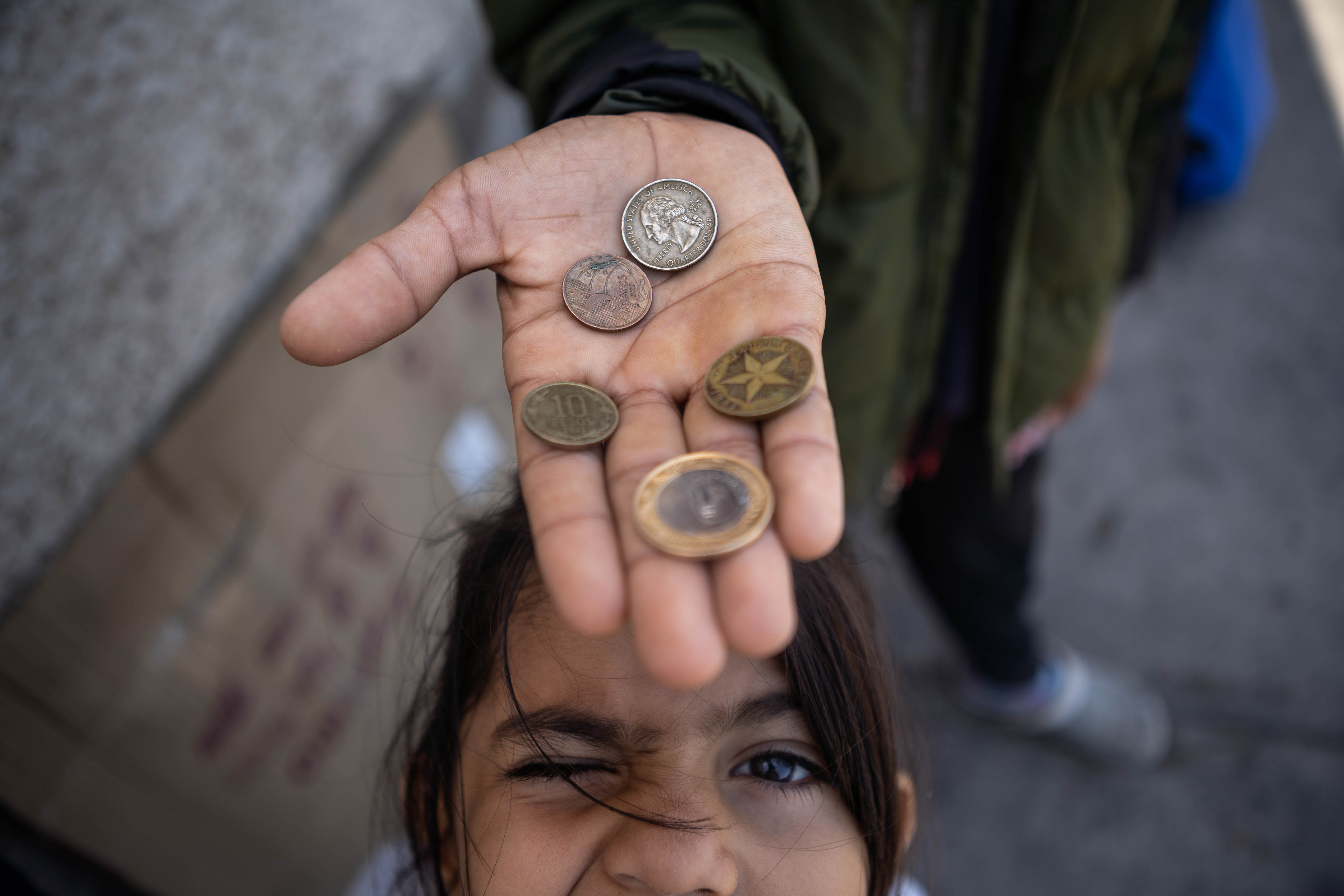 Five-year-old Allyson poses beneath an outstretched hand holding a few coins.