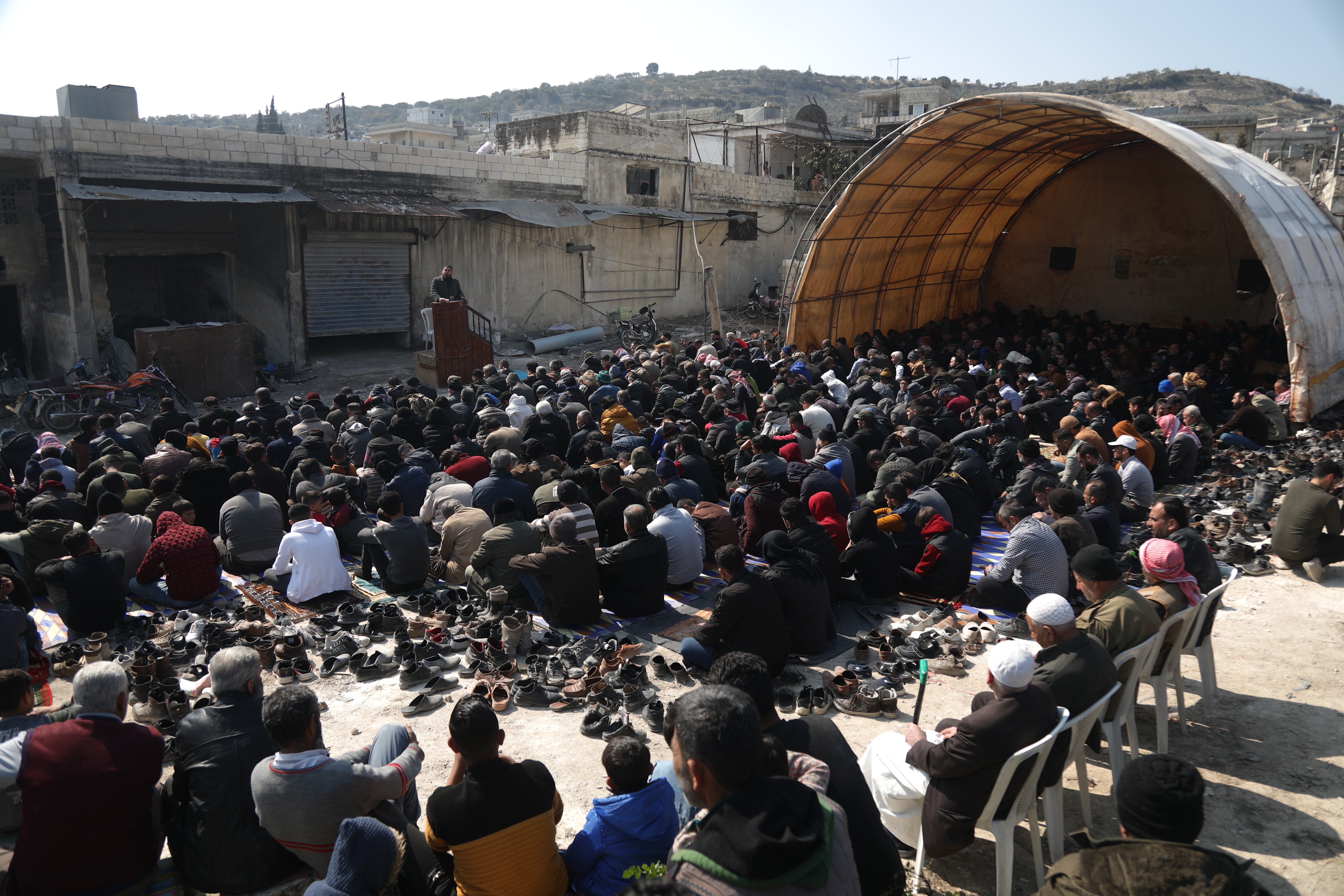 The villagers gathered in a rubble-strewn open area to perform the Friday prayers