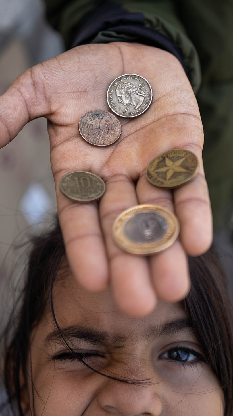 Allyson looks up from beneath an outstretched hand holding a few coins.