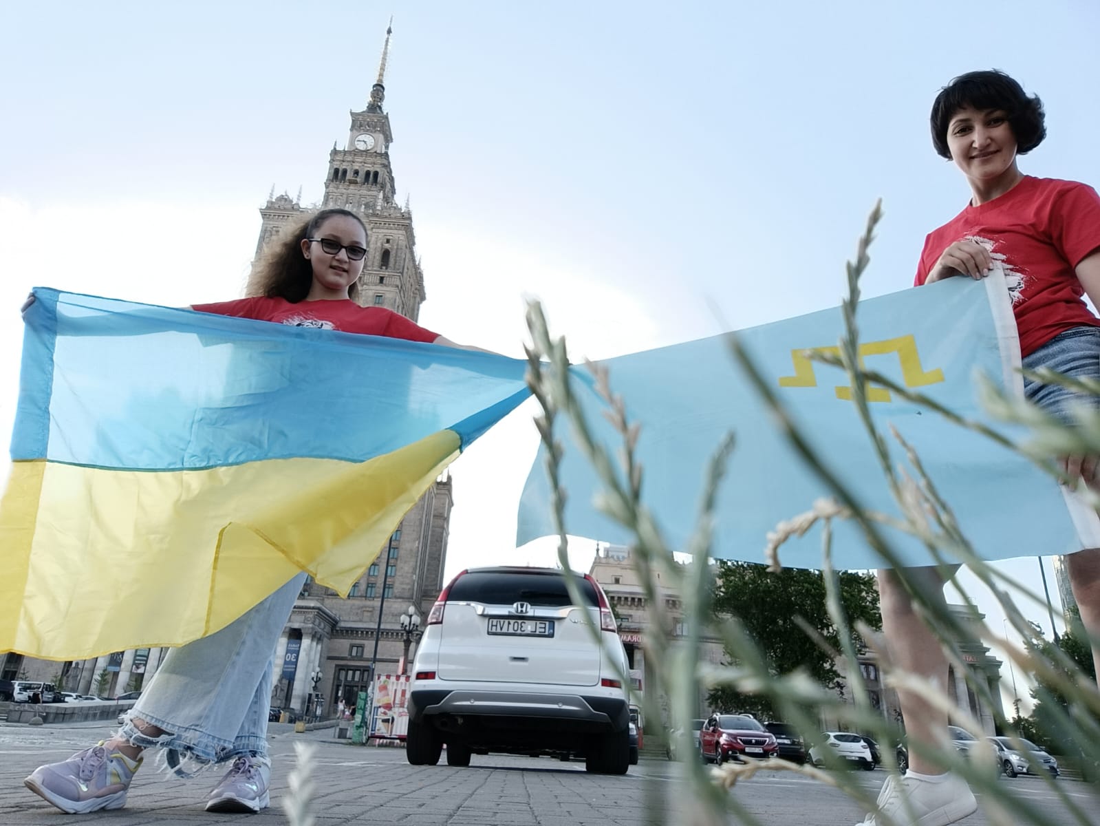 A photo of Samira on the left with a Ukrainian flag and Zakhira on the left holding a Crimean Tatar flag.