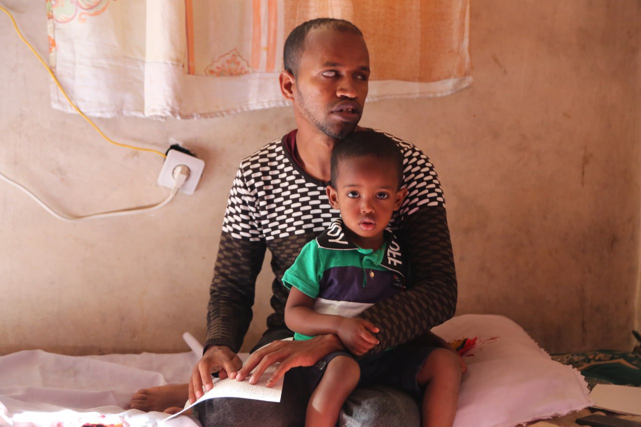 A photo of a man with his son sitting on his lap.
