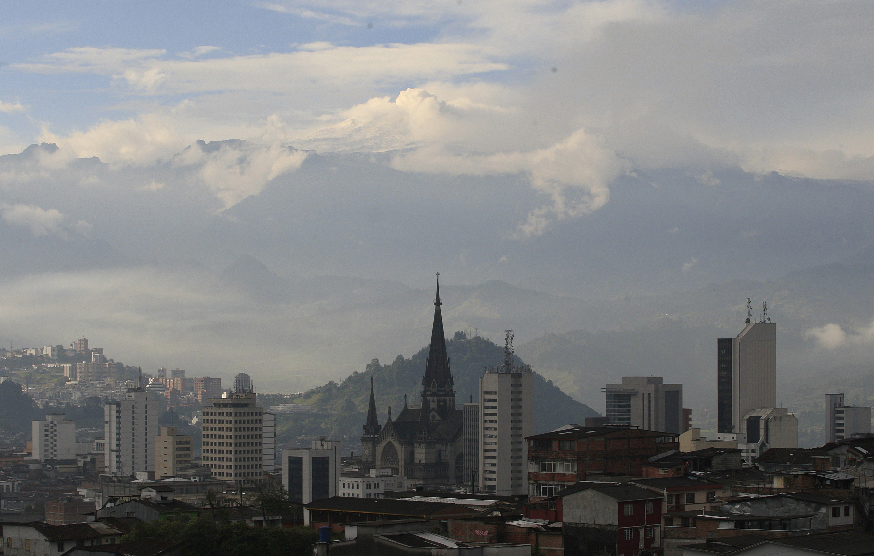 A view of a city skyline, silhouetted against a volcano