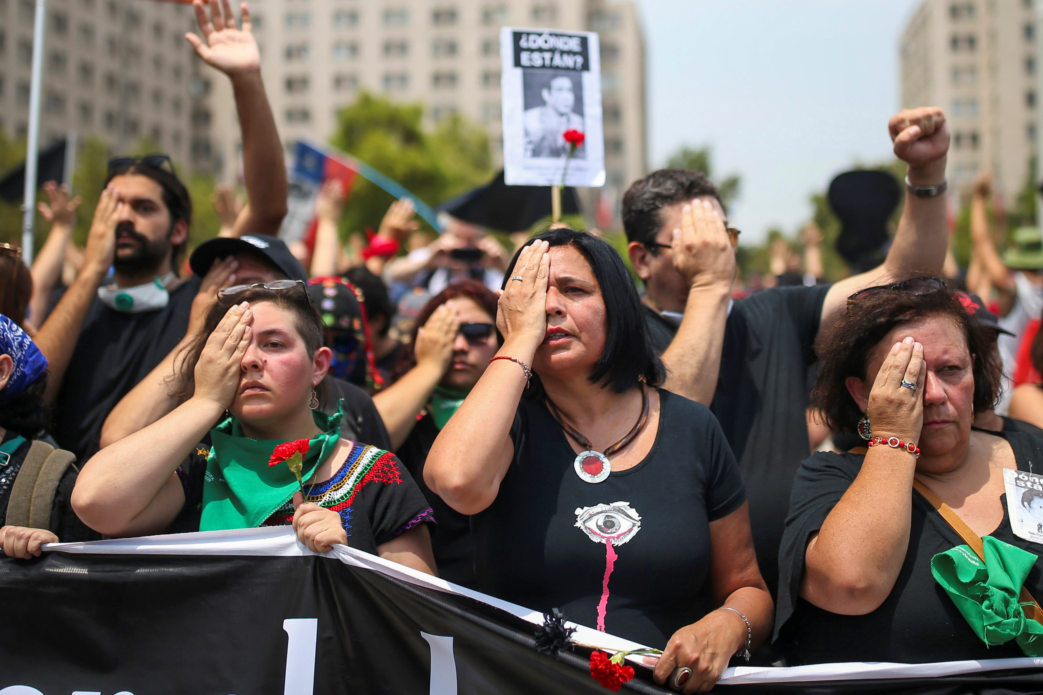 Women cover their eyes in reference to the protesters being blinded by rubber bullets and tear gas, during an anti-government protest in Santiago, Chile, on January 18, 2020.