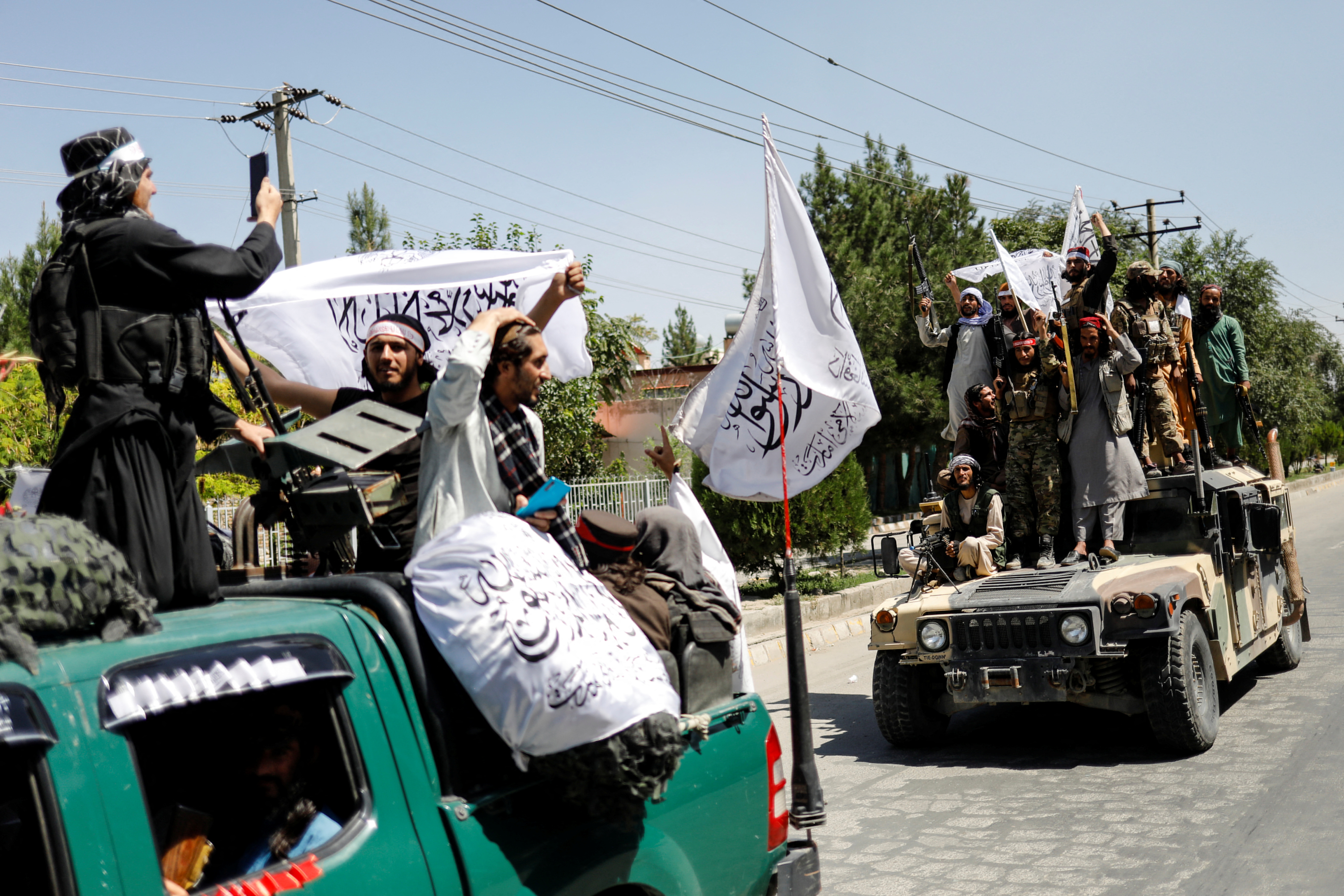 Members of the Taliban ride atop a military vehicle on the first anniversary of the withdrawal of U.S. troops from Afghanistan, on a street in Kabul, Afghanistan, August 31, 2022. REUTERS/Ali Khara