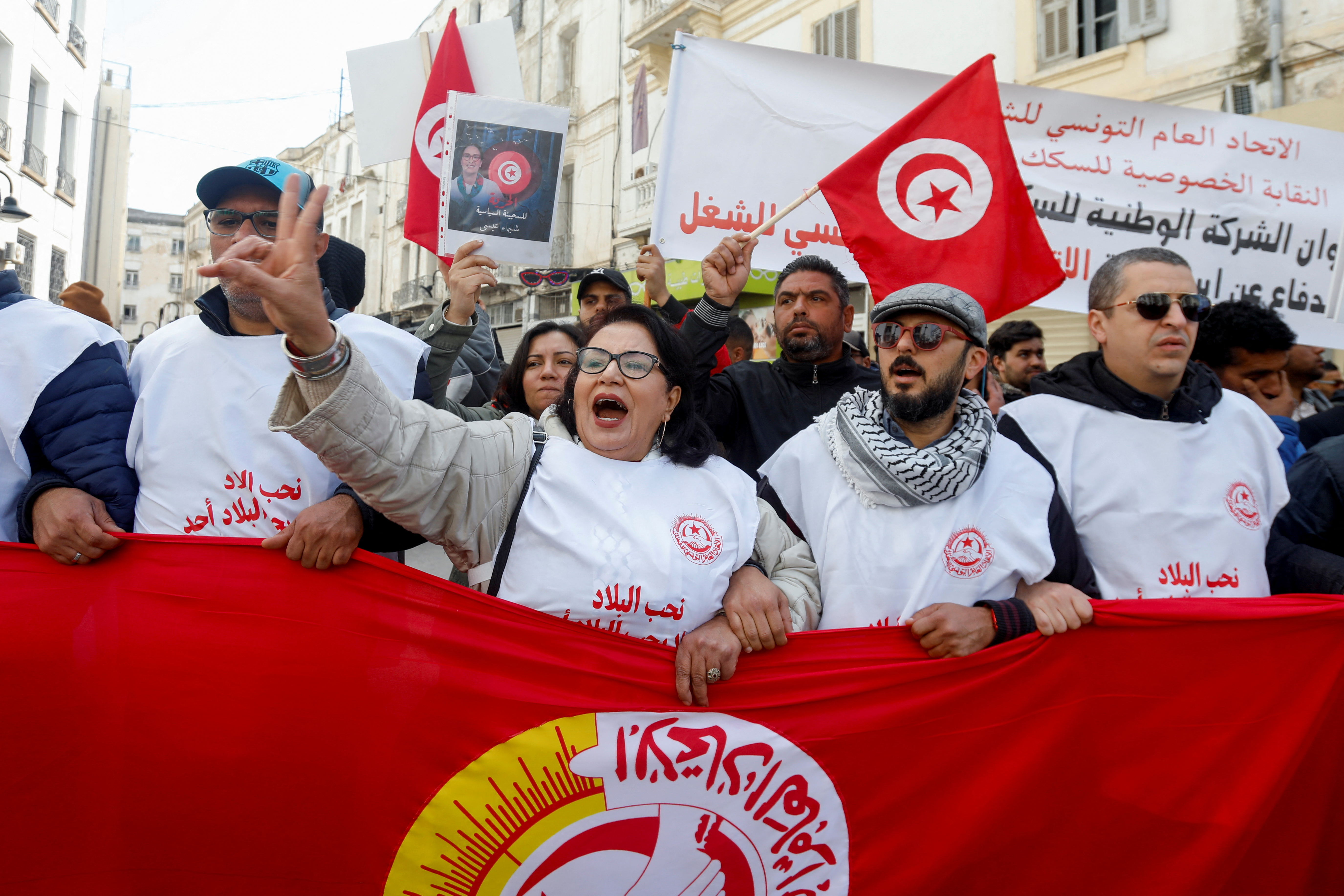 Protesters chant behind a flag at a demonstration